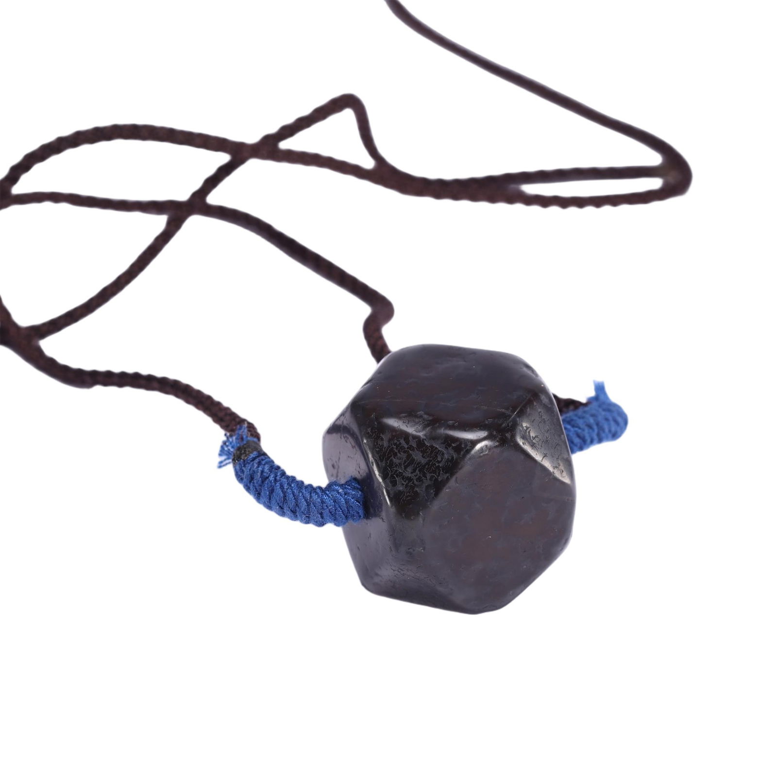 AN AGATE BEAD PENDANT: AN AGATE BEAD PENDANT This Chinese dzi bead pendant necklace features a striking multi-faceted, octagonal dzi bead of deep, rich brown hue, suspended from a dark brown cord with blue-wrapped ends. The