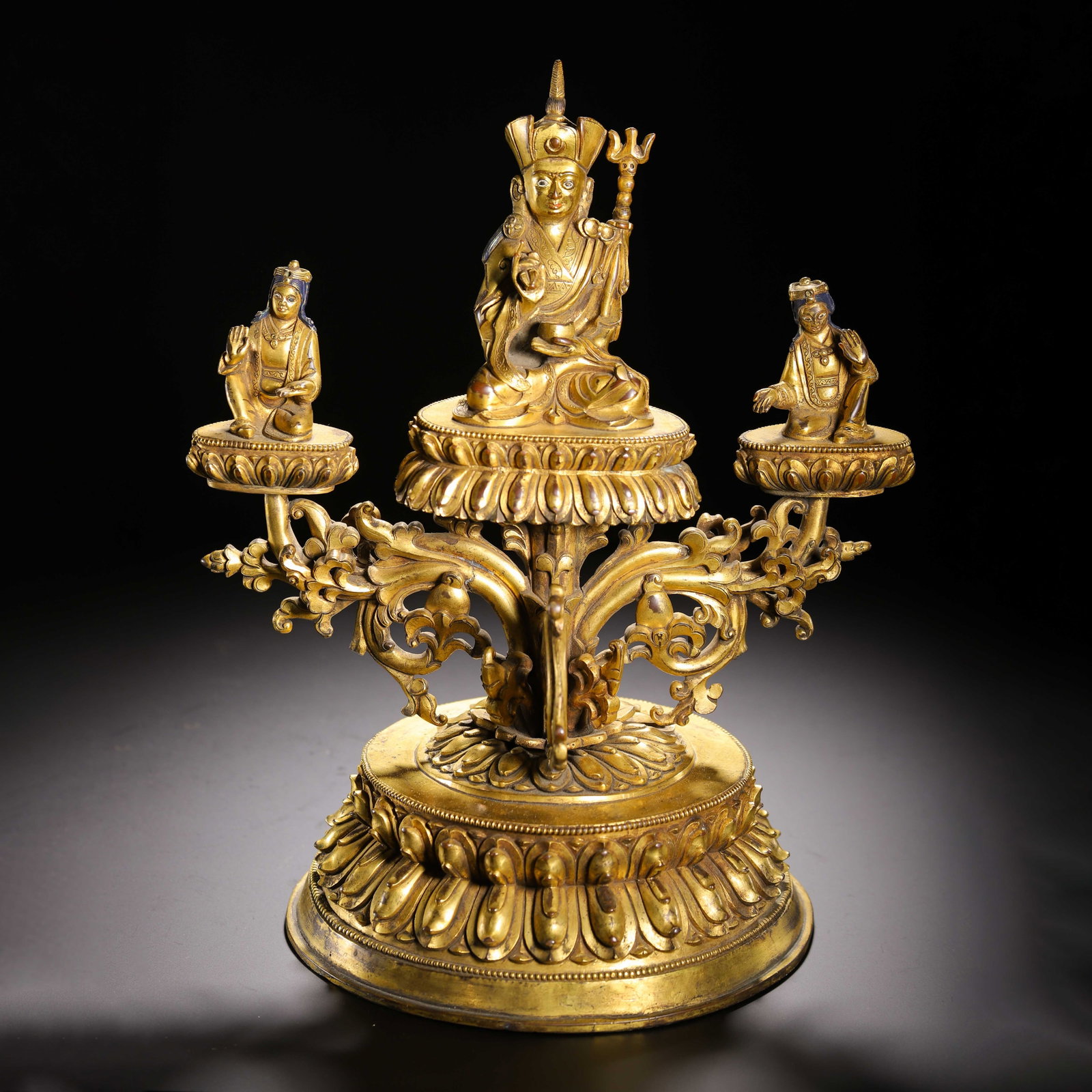 A Chinese Gilt Bronze Buddhist Group: A Chinese Gilt Bronze Buddhist Group This Chinese gilt bronze Buddhist triad measures 24 cm in length, 18.5 cm in width, 29 cm in height, and weighs 3940 grams. The central figure, depicted with cerem