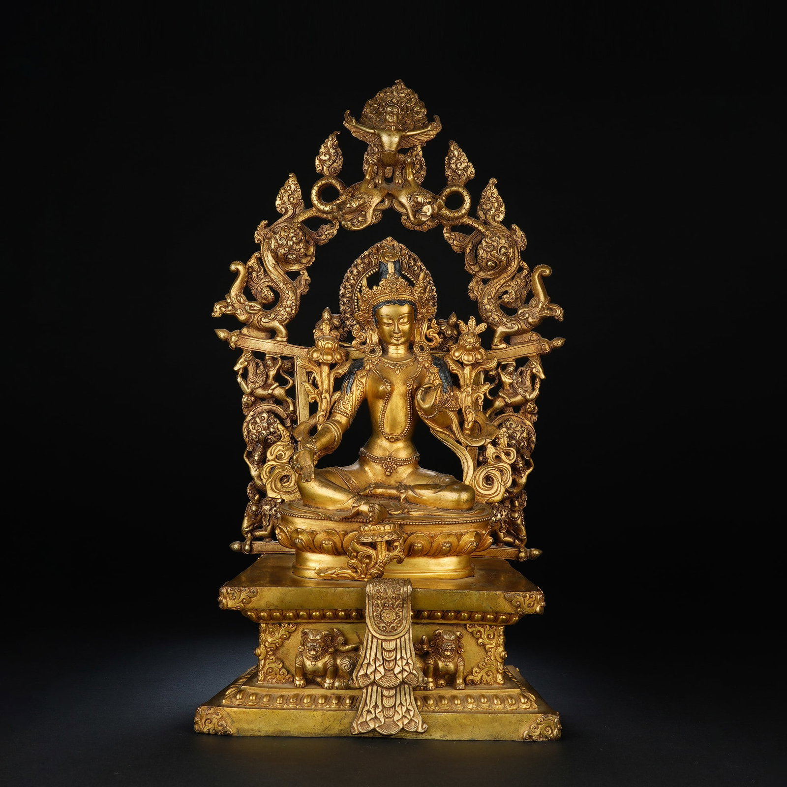 Chinese Gilt Bronze Statue of Tara: Chinese Gilt Bronze Statue of Tara This elaborate gilt bronze statue depicts Tara seated in royal ease pose, adorned with an ornate crown and celestial garments. She holds the stem of a blue lotus in 