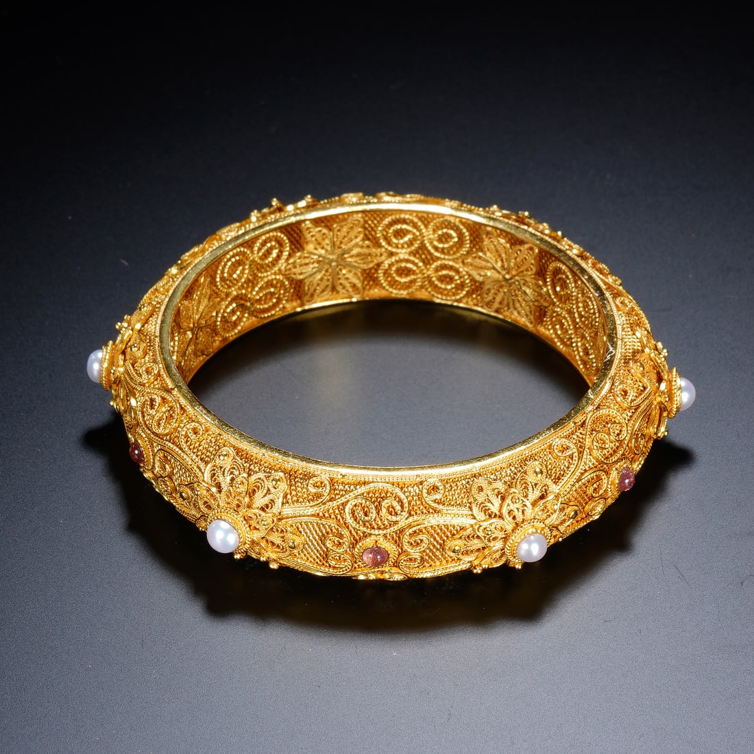 Chinese Gilt Silver Gem-Set Filigree Bangle: Chinese Gilt Silver Gem-Set Filigree Bangle This exquisite bangle is crafted from gilt silver using traditional filigree technique, with intricate openwork scroll and floral patterns adorning both the