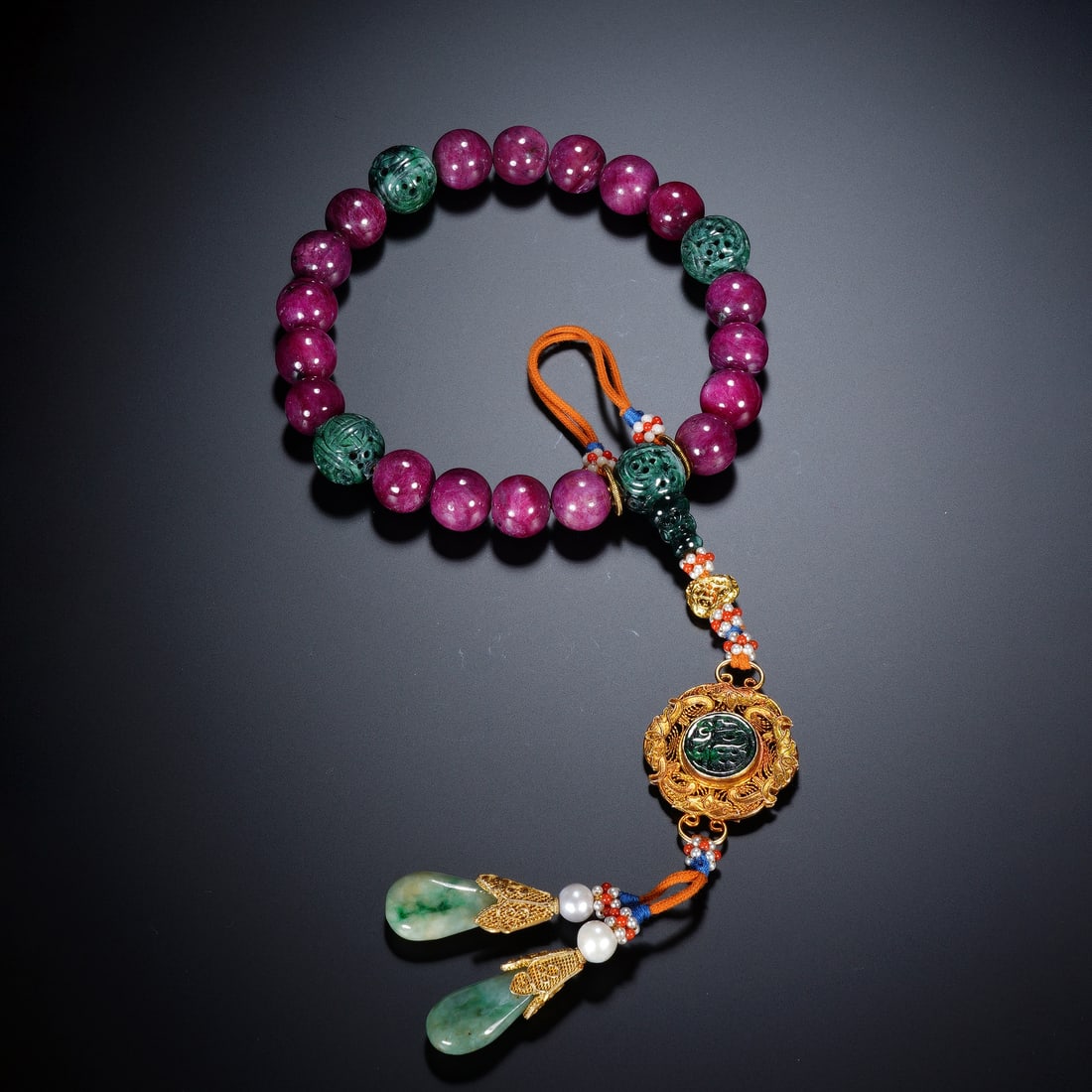 Chinese Ruby Eighteen-Bead Prayer Bracelet: Chinese Ruby Eighteen-Bead Prayer Bracelet This exquisite eighteen-bead bracelet is strung with smooth, polished rubies of a rich magenta hue, interspersed with intricately carved jadeite beads. The p