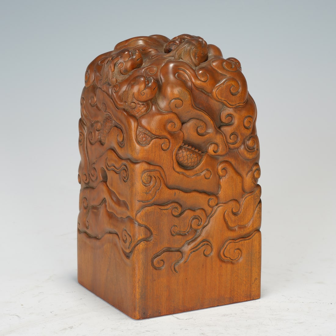 Chinese Sandalwood Dragon Seal: Chinese Sandalwood Dragon Seal This substantial square seal is carved from solid sandalwood, its entire surface adorned in deep relief with writhing dragons emerging from swirling clouds. The top feat