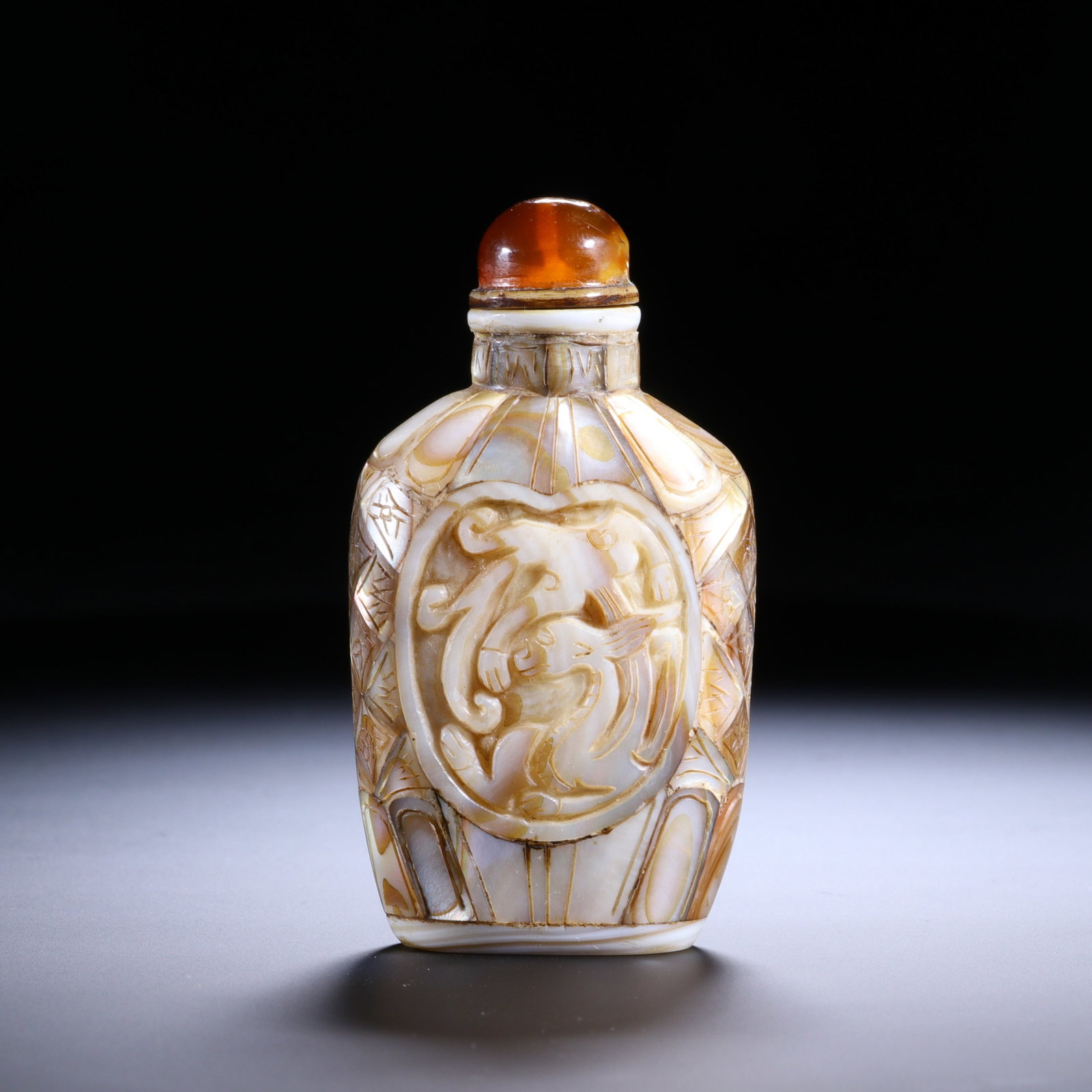A Chinese Mother-of-Pearl Carved Snuff Bottle: A Chinese Mother-of-Pearl Carved Snuff Bottle This finely crafted snuff bottle, standing 8 cm tall and 4.3 cm wide, is meticulously carved from mother-of-pearl, showcasing the material?s natural