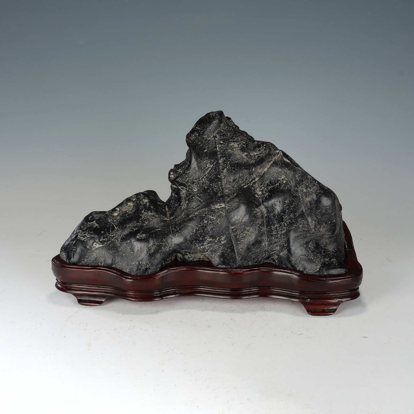Chinese Lingbi Scholar’s Rock: Chinese Lingbi Scholar’s Rock This impressive Chinese scholar’s rock is a naturally formed Lingbi stone, celebrated for its dramatic mountain-like silhouette and richly textured surface. The deep