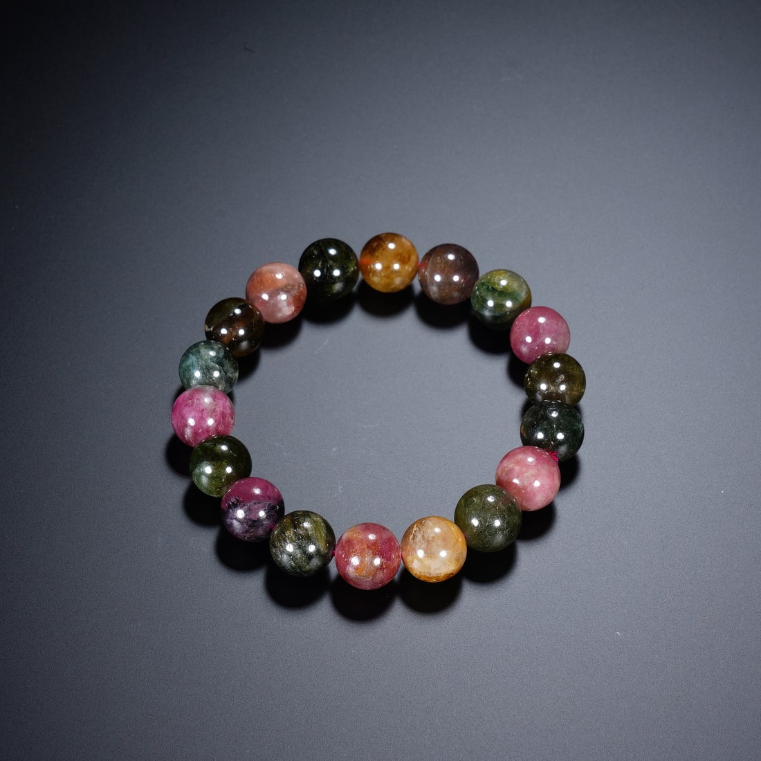 Chinese Tourmaline Beaded Bracelet: Chinese Tourmaline Beaded Bracelet This vibrant bracelet is composed of eighteen round tourmaline beads, exhibiting a rich spectrum of natural colors including deep green, rose pink, warm yellow, and 