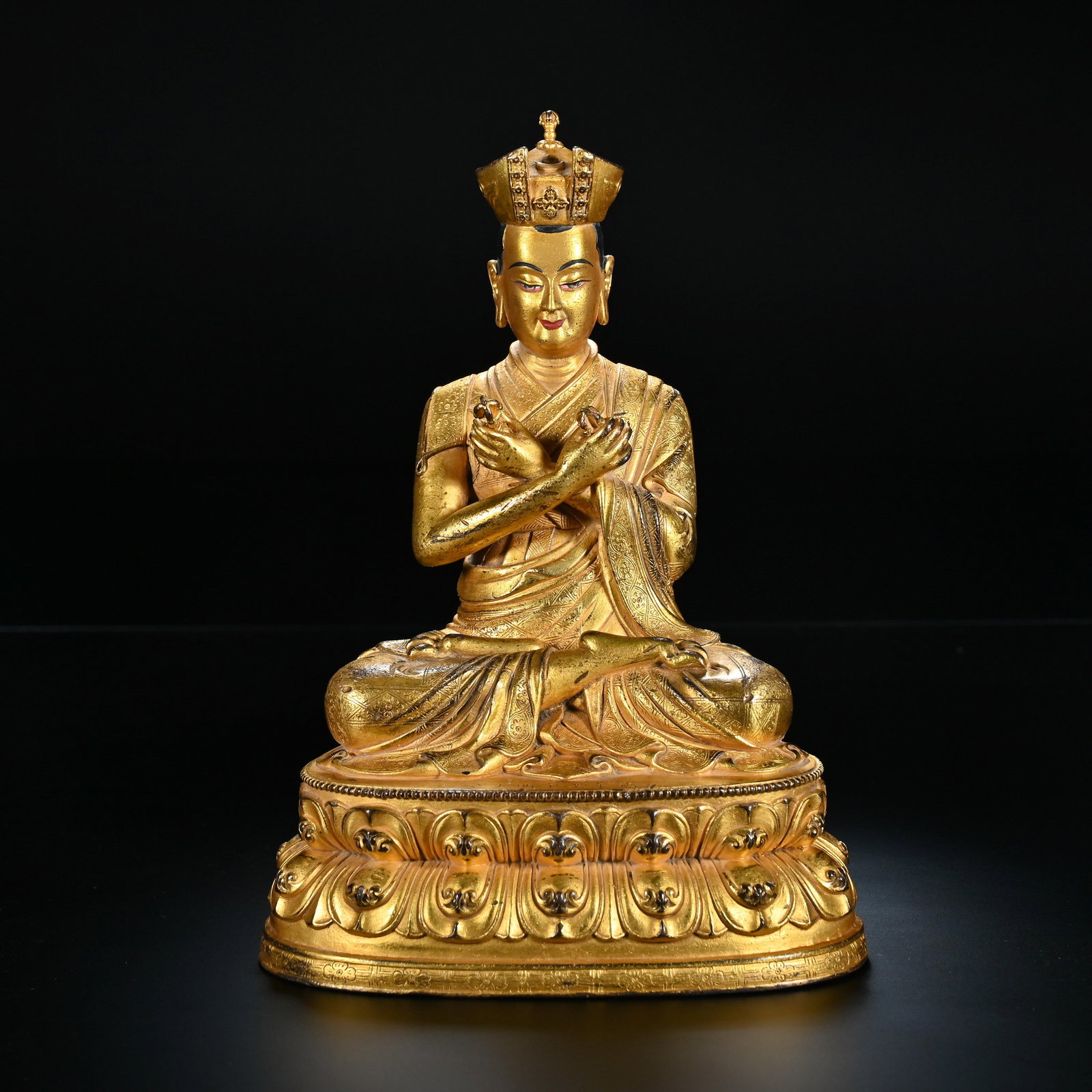 A Chinese Gilt-Bronze Seated Lama Statue: A Chinese Gilt-Bronze Seated Lama Statue This finely crafted gilt-bronze statue, measuring 18.5 cm in height and 11.5 cm in width, depicts a seated lama in a meditative lotus position. The figure wear