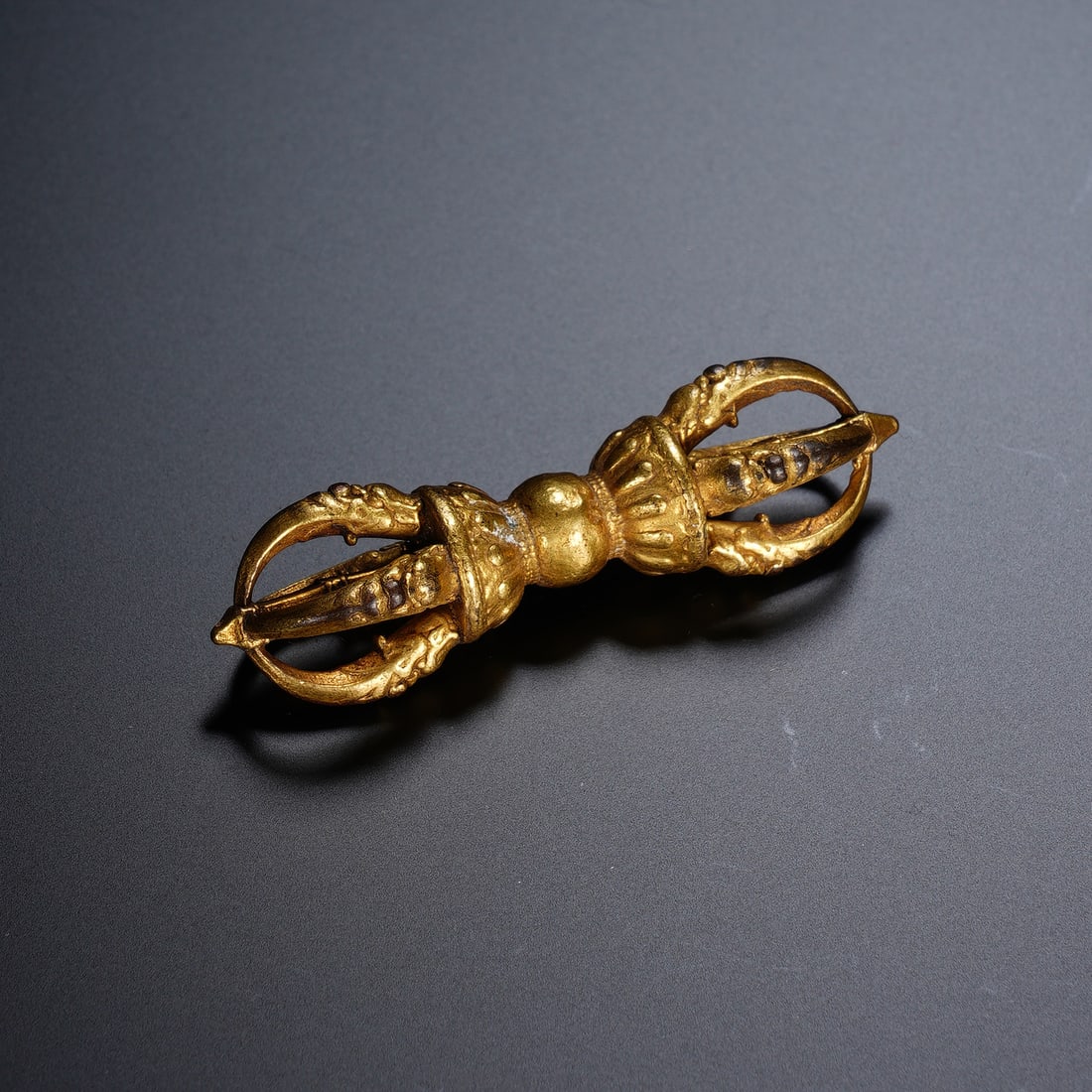 Chinese Gilt-Bronze Five-Pronged Vajra: Chinese Gilt-Bronze Five-Pronged Vajra This small yet precisely crafted five-pronged vajra is cast in bronze with a rich, lustrous gilded finish. It features symmetrical, stylized prongs at each end, 