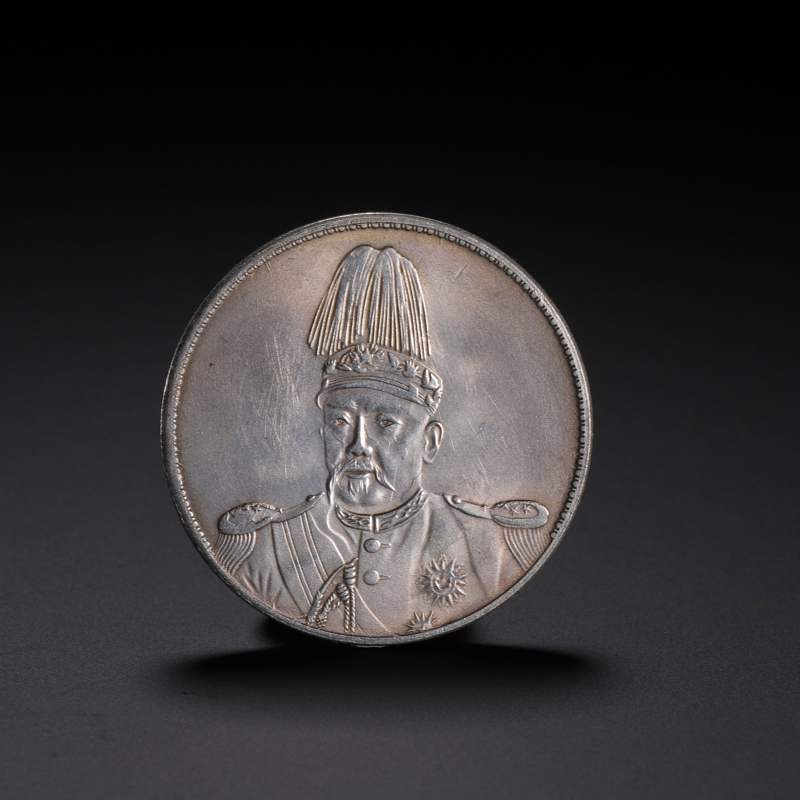 Chinese Silver Commemorative Coin: Chinese Silver Commemorative Coin A Chinese silver coin featuring a detailed portrait of a historical figure in military attire with a plumed hat and epaulettes, set against a smooth silver field. The