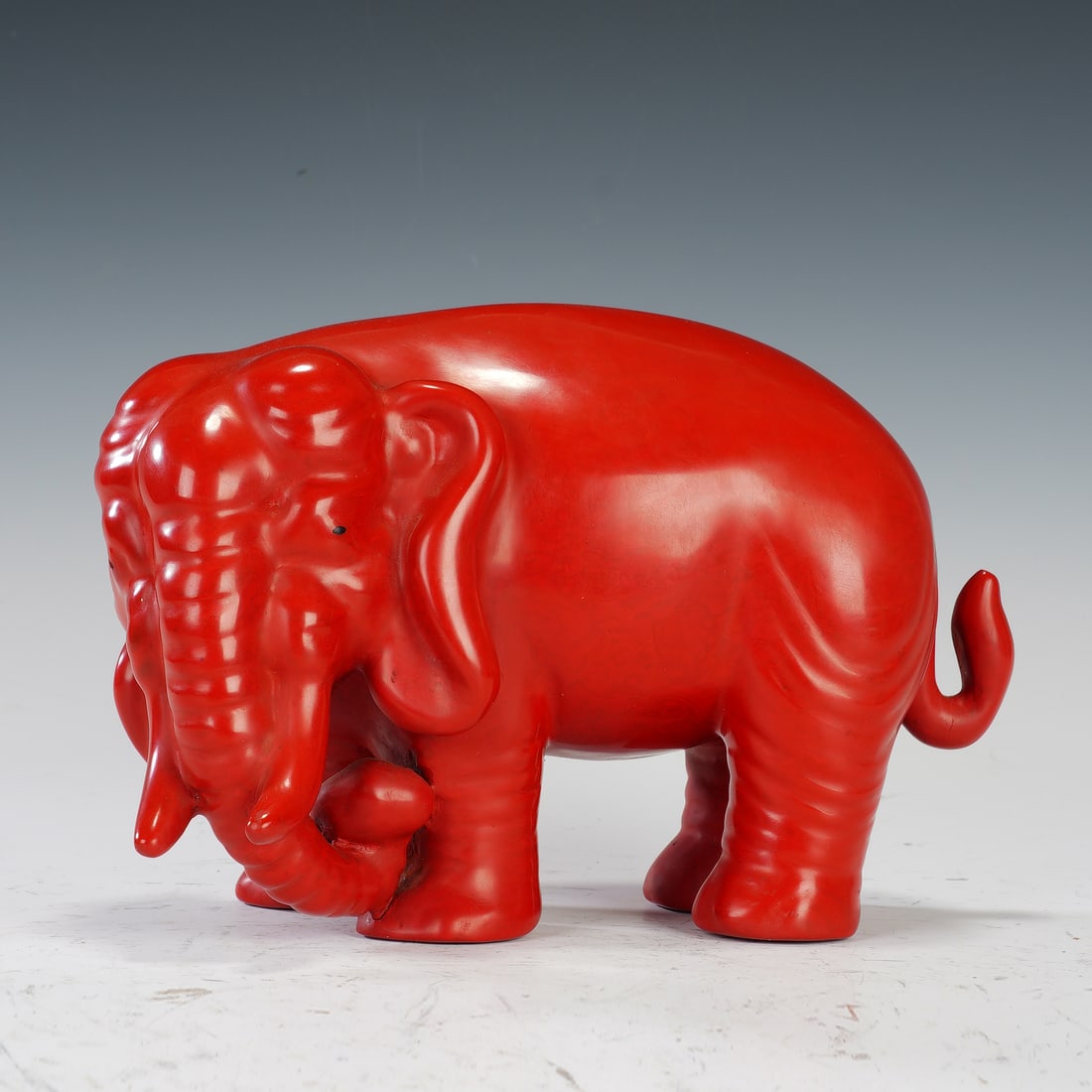 Chinese Lacquered Elephant Ornament: Chinese Lacquered Elephant Ornament This vibrant red lacquered elephant figure, a Republican-period decorative piece, symbolizes peace and good fortune. Its smooth, high-gloss finish accentuates the e