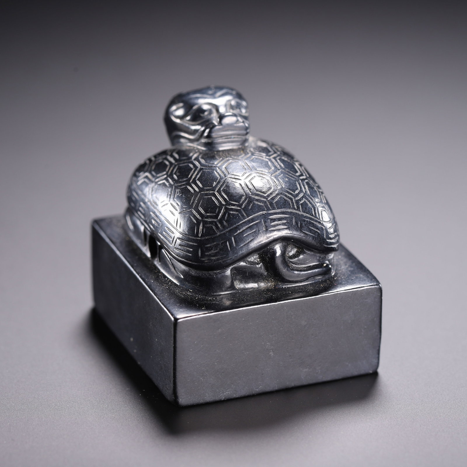 A Chinese Black Hetian Jade Tortoise Seal: A Chinese Black Hetian Jade Tortoise Seal This Chinese black Hetian jade seal measures 4.1 cm in length, 3.6 cm in width, and 4 cm in height. The square seal is topped with a finely carved tortoise fi