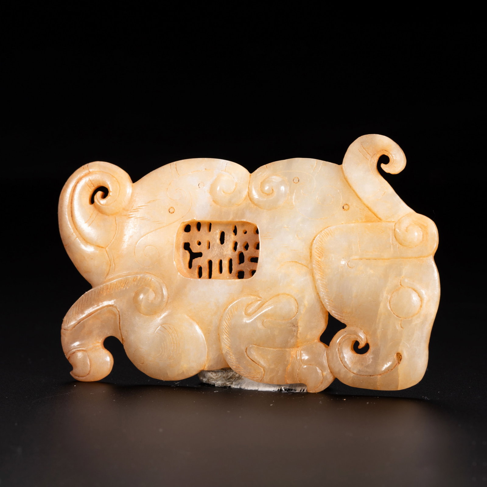 A Chinese Hetian Jade Animal Form Pendant: A Chinese Hetian Jade Animal Form Pendant A finely carved Chinese Hetian jade animal-form pendant, rendered in a stylized mythical beast silhouette with dynamic, curving appendages. The pale, creamy-w
