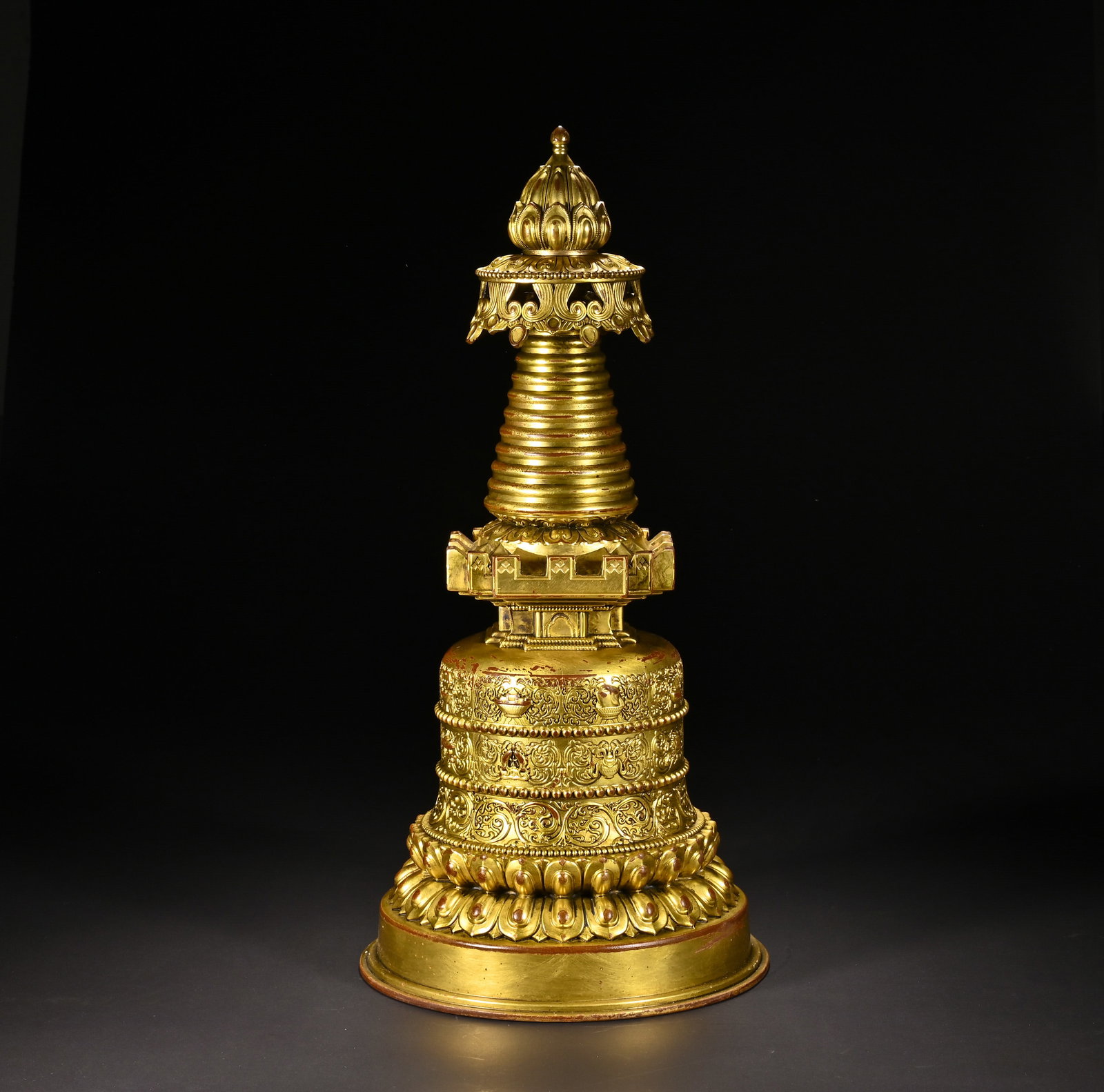 A Chinese Gilt-Bronze Buddhist Stupa: A Chinese Gilt-Bronze Buddhist Stupa This imposing gilt-bronze Buddhist stupa, measuring 44 cm in height and 22 cm in width, is crafted in traditional Tibetan Buddhist style. The multi-tiered structur