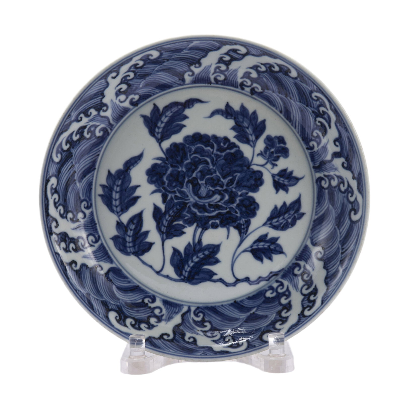 A BLUE AND WHITE PEONY PATTERN PORCELAIN DISH: A BLUE AND WHITE PEONY PATTERN PORCELAIN DISH The shallow-rounded sides rising from a flat base and a tapered foot, painted on the interior with a peony-bouquet surrounded with a band of foaming waves
