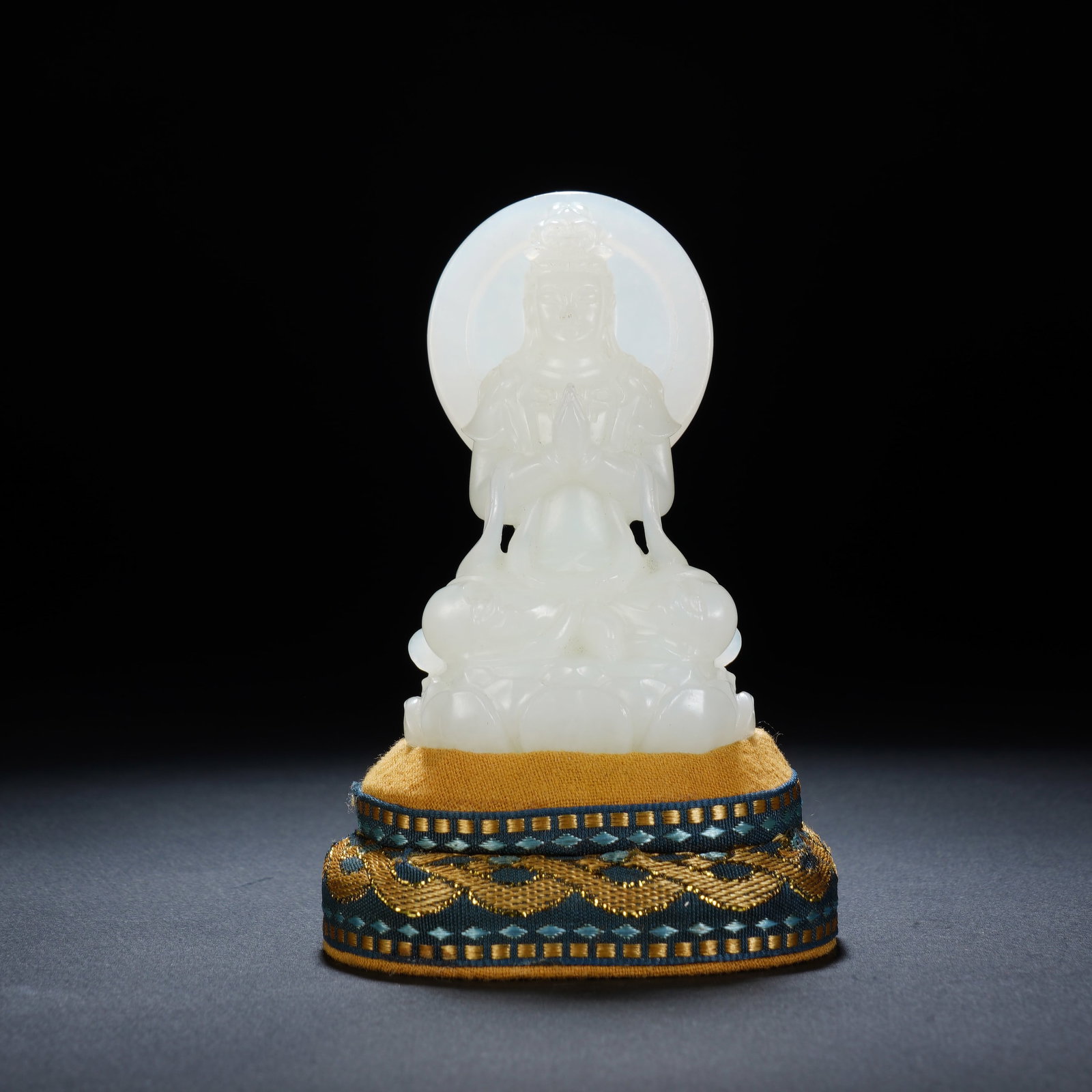 A CHINESE WHITE JADE GUANYIN FIGURE: A CHINESE WHITE JADE GUANYIN FIGURE This carved white nephrite Guanyin statue measures 4.8 cm wide, 3 cm deep and 8.5 cm tall, weighing 105 grams. The deity is depicted seated atop a layered lotus thr