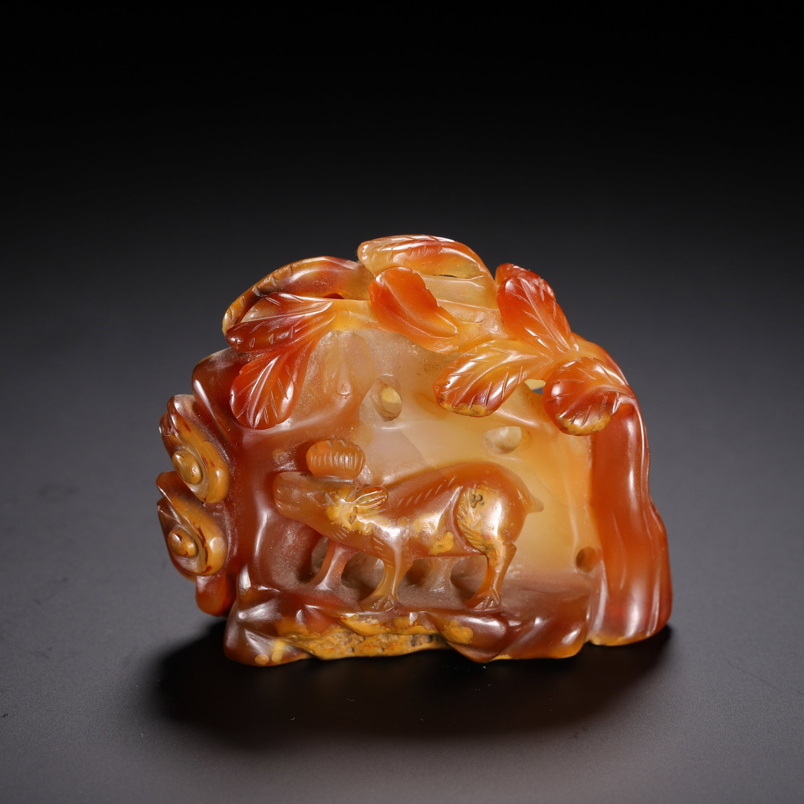 A CHINESE AGATE DEER LANDSCAPE BOULDER ORNAMENT: A CHINESE AGATE DEER LANDSCAPE BOULDER ORNAMENT This miniature mountain carving is crafted from natural agate featuring warm gradients of amber, russet and translucent honey tones. Openwork hollowed