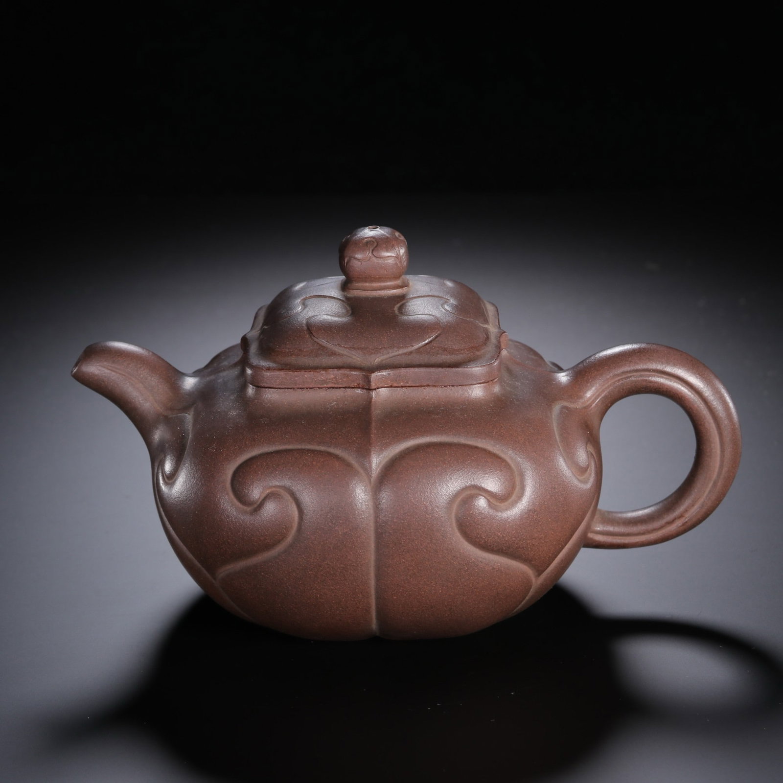 A CHINESE RUYI PATTERN ZISHA TEAPOT: A CHINESE RUYI PATTERN ZISHA TEAPOT Expertly shaped from fine purplish zisha clay, this teapot features an elegant segmented form fully adorned with raised relief ruyi scroll motifs, the timeless symb
