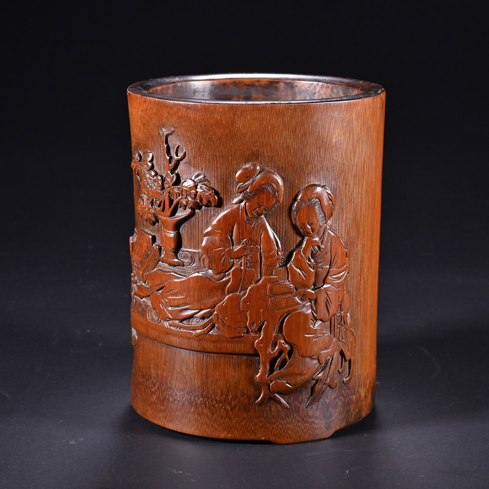 A CHINESE CARVED BAMBOO LADIES BRUSH POT: A CHINESE CARVED BAMBOO LADIES BRUSH POT This cylindrical literati brush pot is crafted from aged solid bamboo with a warm deep amber patina formed by long-term handling. Its exterior features elabora