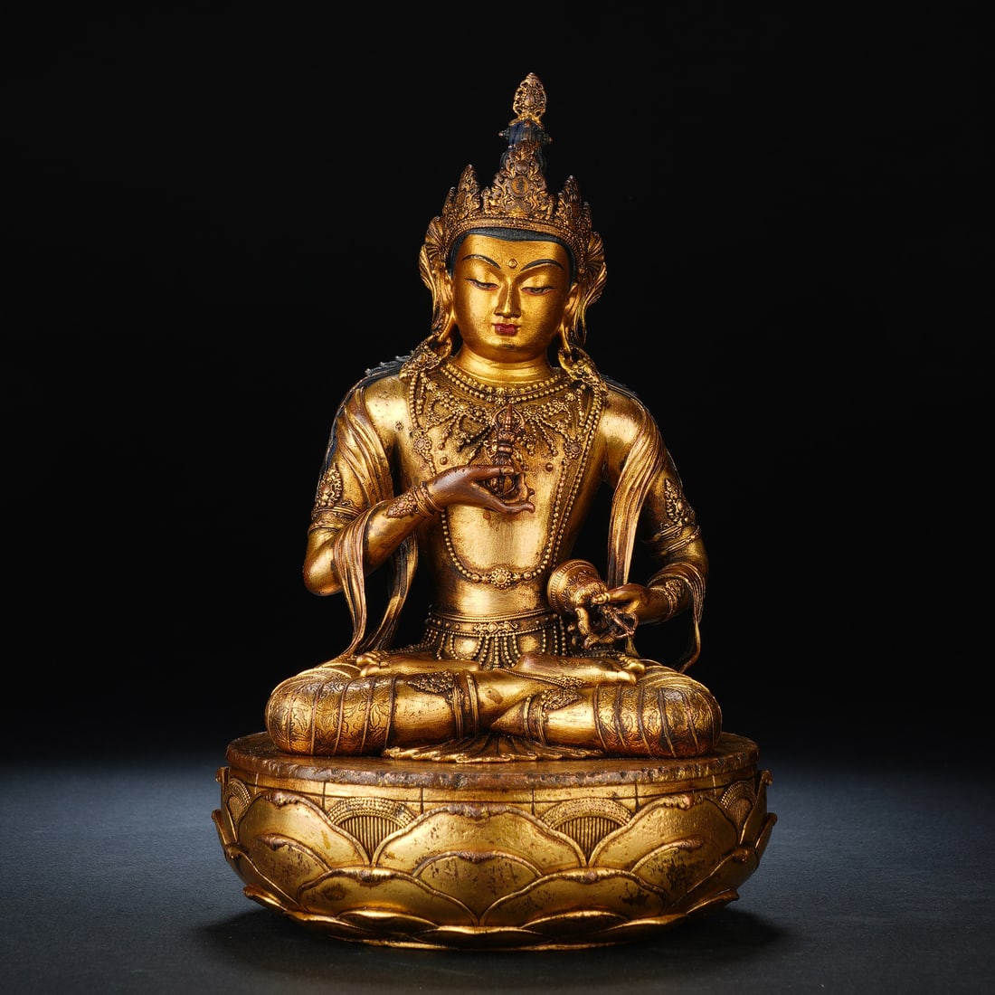 A CHINESE GILT BRONZE VAJRASATTVA BODHISATTVA: A CHINESE GILT BRONZE VAJRASATTVA BODHISATTVA Masterfully cast bronze entirely gilded in fine gold, this seated Vajrasattva Bodhisattva rests atop an elaborately moulded lotus throne. The deity wears 