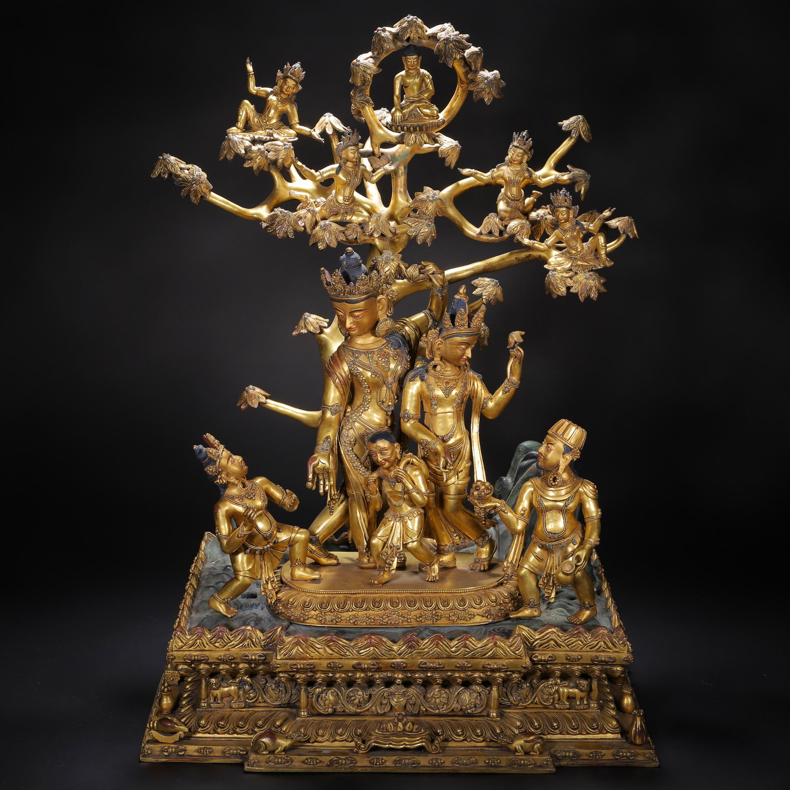 A CHINESE GILT BRONZE BUDDHIST ASSEMBLY GROUP: A CHINESE GILT BRONZE BUDDHIST ASSEMBLY GROUP This monumental fully gilded copper figural group features multiple crowned bodhisattvas standing beneath an elaborate sacred tree laden with attendant ce