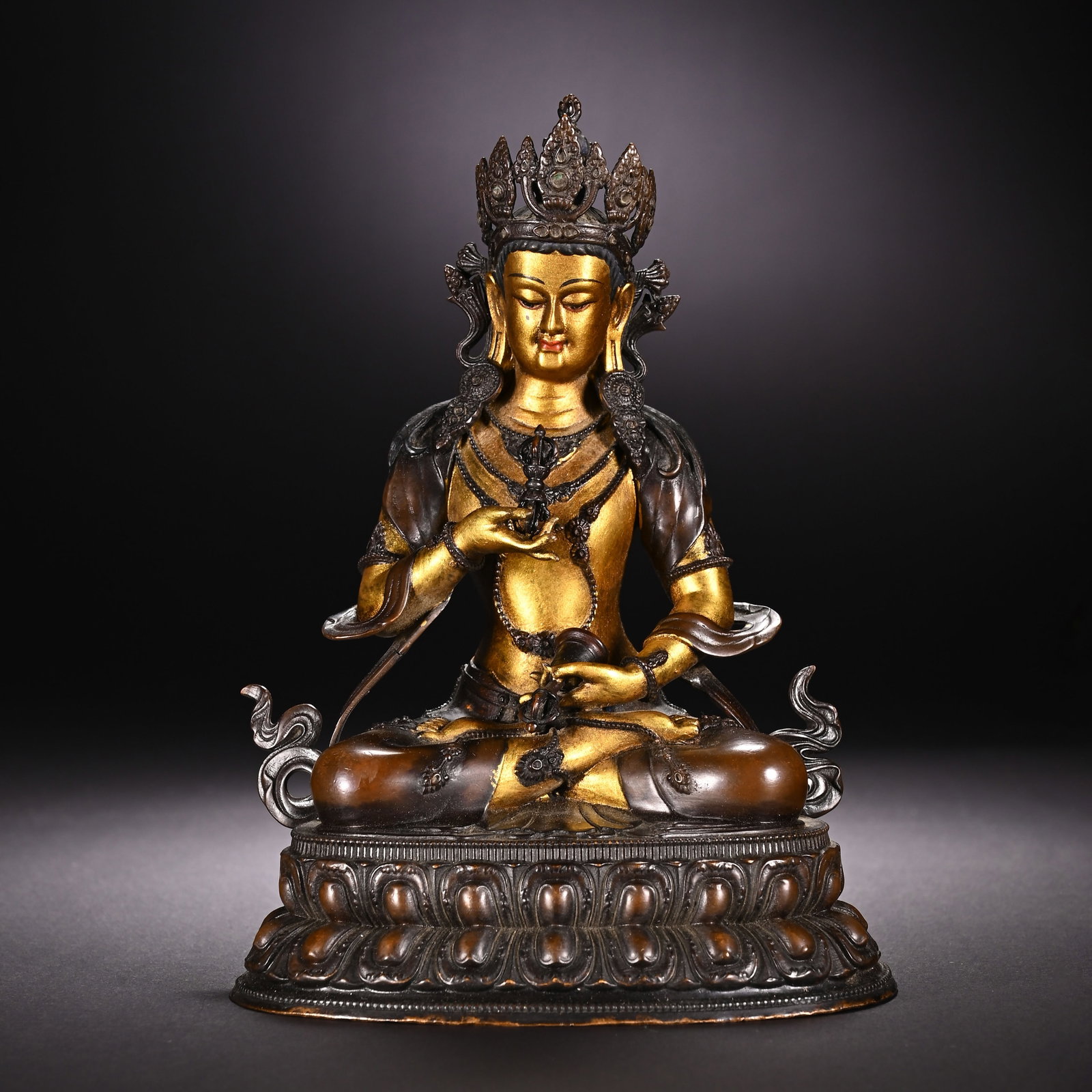 A CHINESE PARTIALLY GILT BRONZE VAJRASATTVA STATUE: A CHINESE PARTIALLY GILT BRONZE VAJRASATTVA STATUE This tantric Buddhist figure of Vajrasattva is cast in bronze with selective gilding on the face, chest and hands, contrasted against dark patinated 