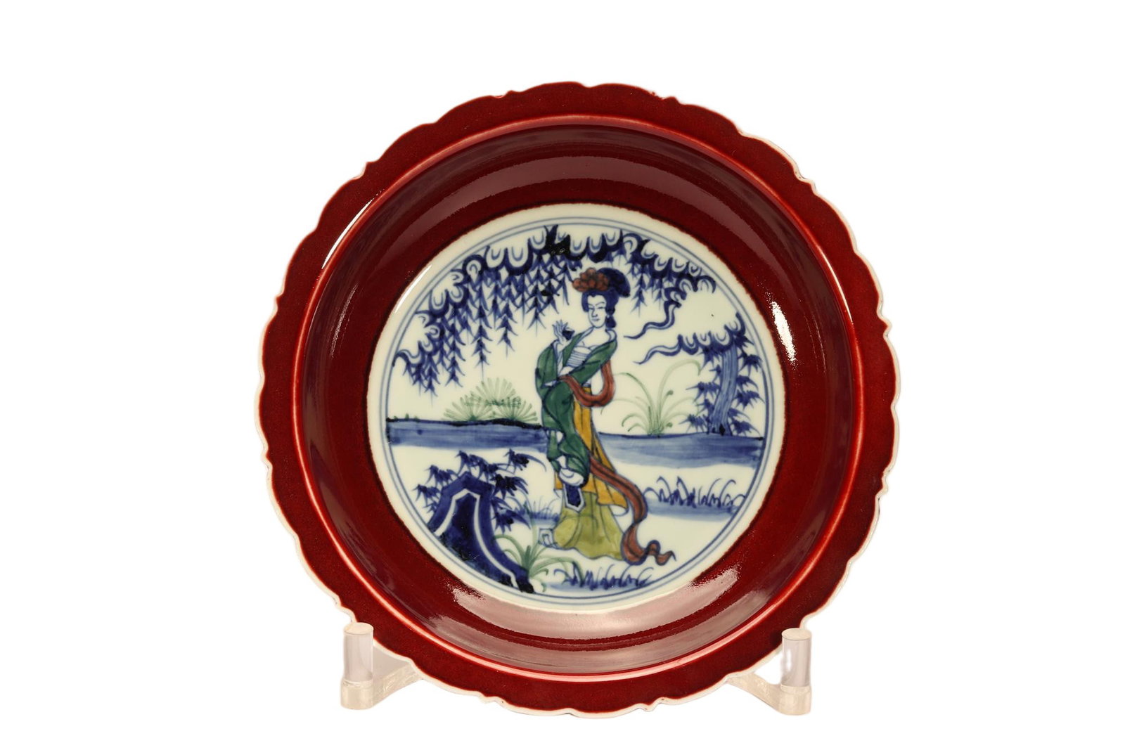 A CHINESE SACRIFICIAL RED GLAZE FIGURAL LOBED PLATE: A CHINESE SACRIFICIAL RED GLAZE FIGURAL LOBED PLATE This scalloped-rim plate boasts a rich, glossy sacrificial red glaze covering its wide outer cavetto and rim, forming a striking border against the 