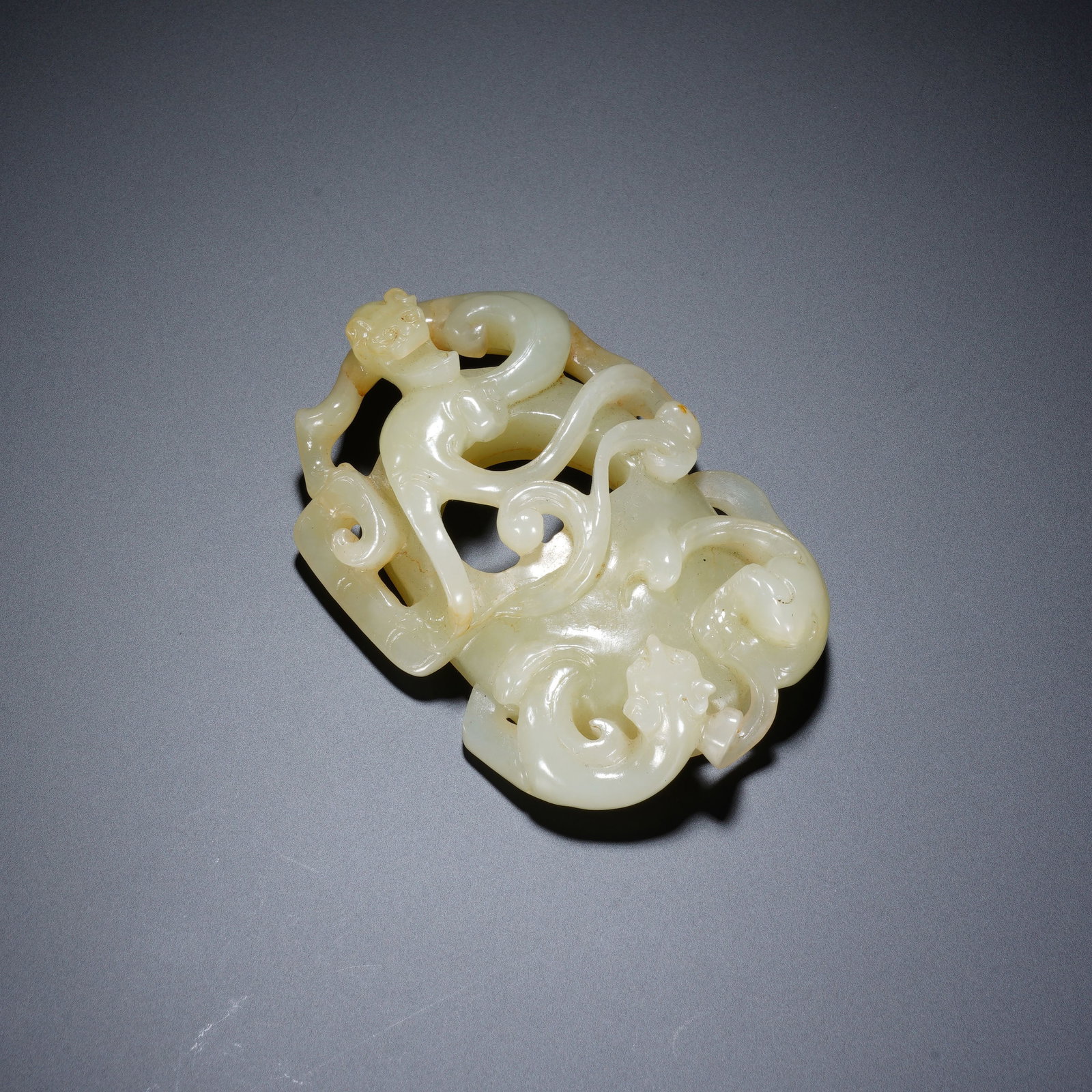 A CHINESE JADE BELT PLAQUE WITH COILED CHILONG DRAGONS: A CHINESE JADE BELT PLAQUE WITH COILED CHILONG DRAGONS This openwork jade belt ornament measures 7.5cm ? 5cm ? 2cm and weighs 66 grams. Crafted from smooth pale celadon jade with faint russet inclusio
