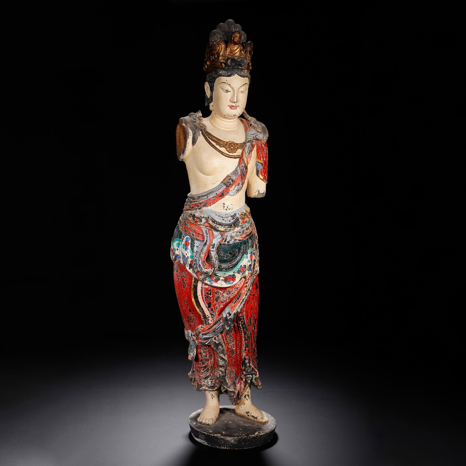 A CHINESE POLYCHROME WOOD GUANYIN STATUE: A CHINESE POLYCHROME WOOD GUANYIN STATUE This standing Guanyin figure is carved from solid wood and finished with layered mineral polychrome pigments and gilded accents. The bodhisattva wears an ornat