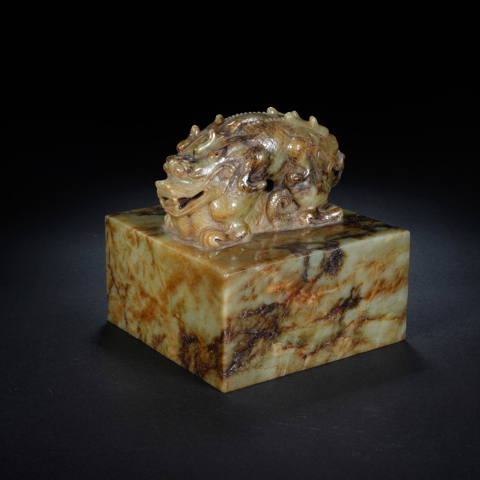 A CHINESE HETIAN JADE DRAGON SEAL: A CHINESE HETIAN JADE DRAGON SEAL This massive square Hetian jade seal measures 11 cm in all dimensions, weighing 2241 grams. The solid cubic block features natural mottled celadon stone permeated wit