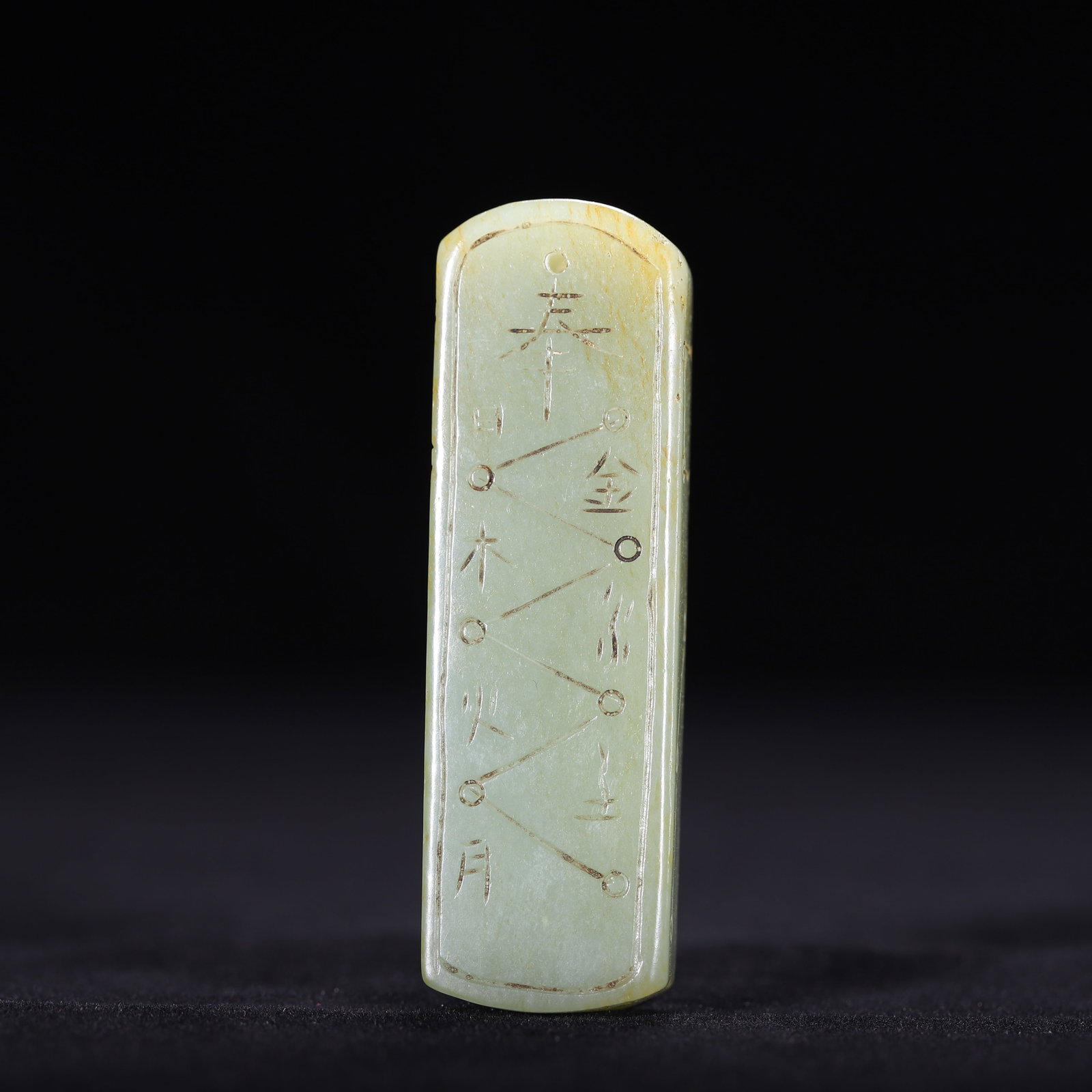 A CHINESE HETIAN JADE TABLET: A CHINESE HETIAN JADE TABLET This slender rectangular pendant is carved from pale celadon Hetian nephrite jade with faint natural yellowish russet patina scattered across the surface. One face is fine