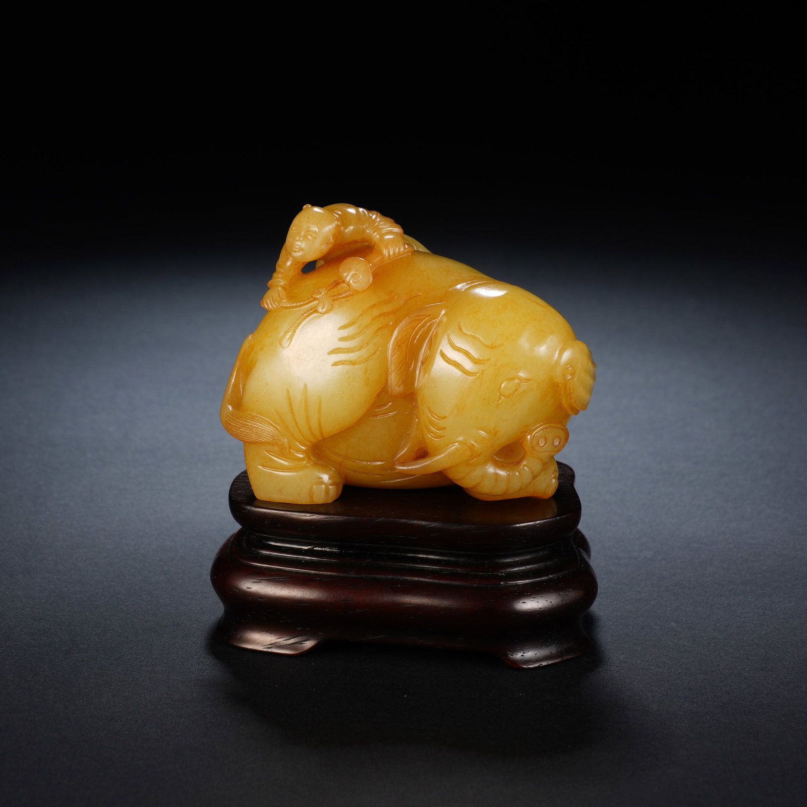 A CHINESE YELLOW NEPHRITE ELEPHANT GROUP: A CHINESE YELLOW NEPHRITE ELEPHANT GROUP This warm golden-yellow nephrite carving measures 7 cm long, 5 cm wide and 6 cm tall, with an overall display height of 9 cm including the stand, weighing 271 