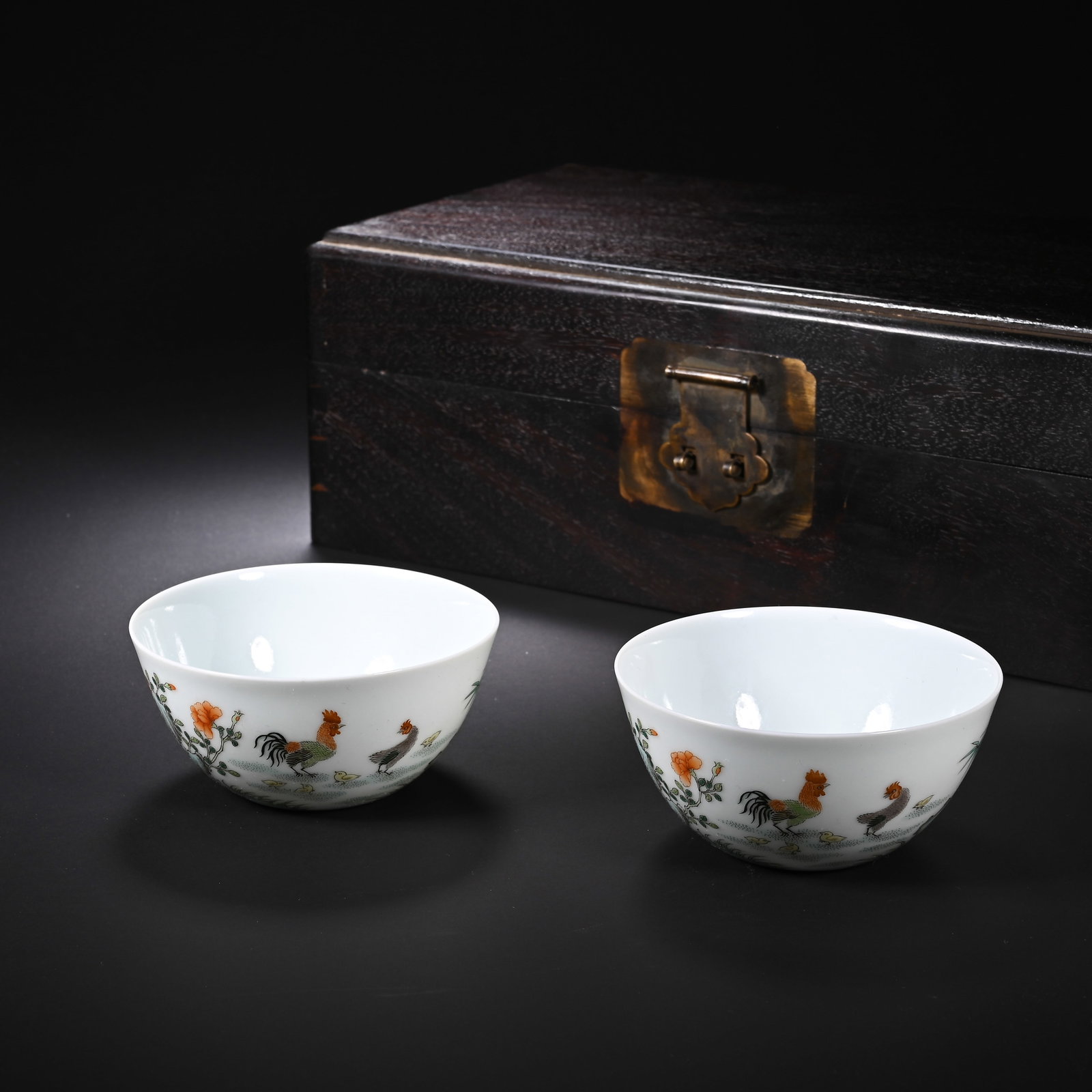 A PAIR OF CHINESE FAMILLE VERTE CHICKEN CUPS: A PAIR OF CHINESE FAMILLE VERTE CHICKEN CUPS This matched pair of chicken cups is crafted from fine translucent white porcelain with gently curved shallow bodies and thin neat rims. The exterior is vi