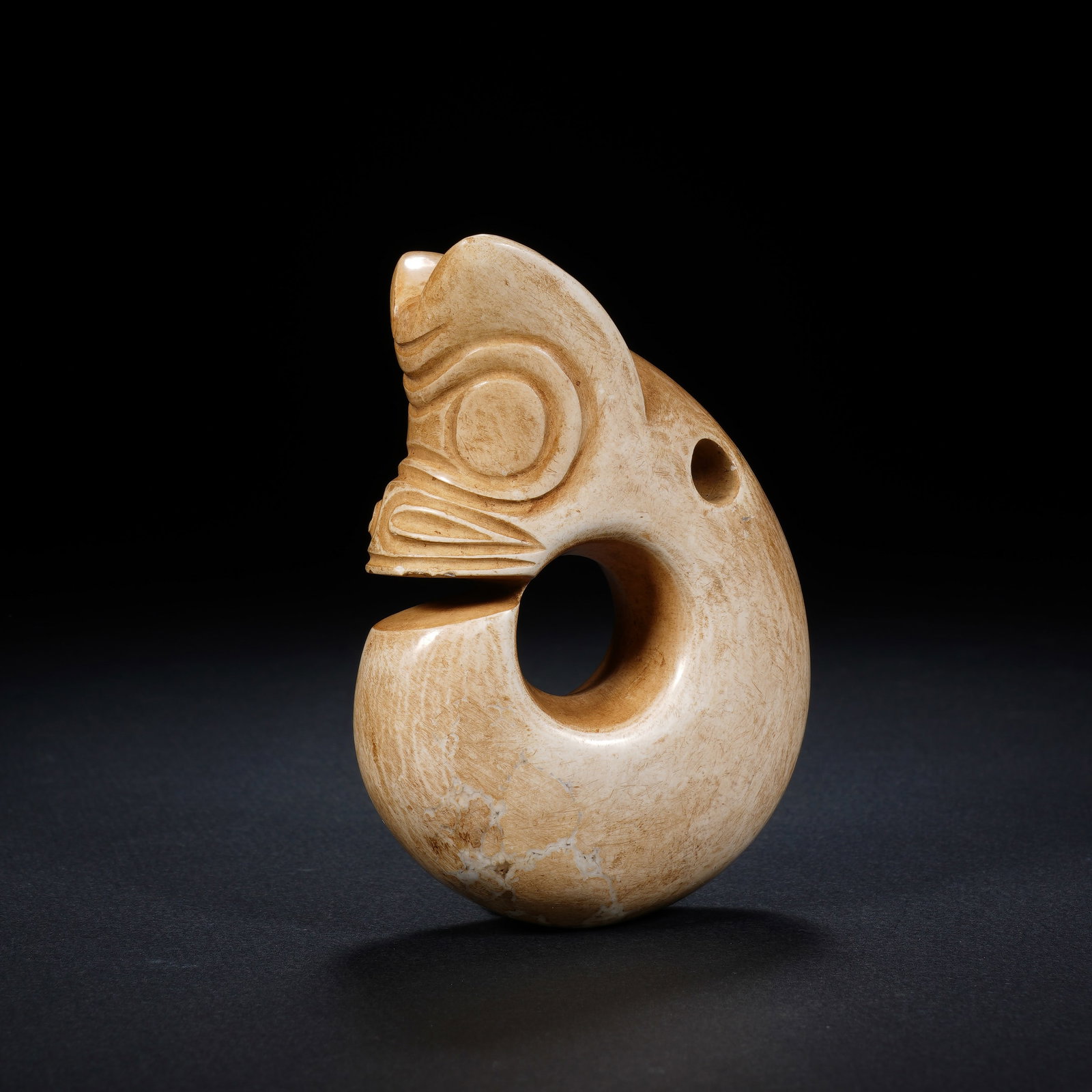 A CHINESE ARCHAIC C-SHAPED JADE PIG DRAGON: A CHINESE ARCHAIC C-SHAPED JADE PIG DRAGON This jade pig dragon pendant measures 6cm ? 3cm ? 8.5cm and weighs 160 grams. It takes the iconic coiled C-form with a characteristic split jaw between the b