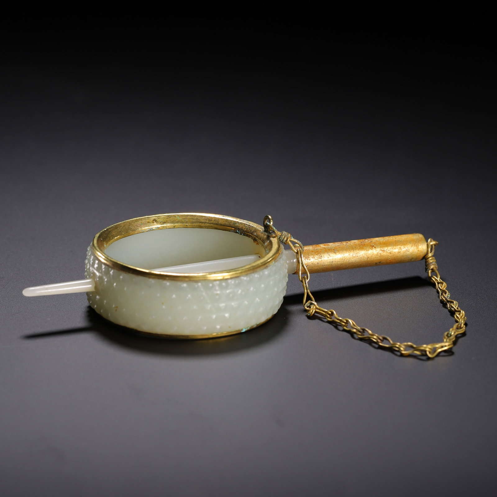 A CHINESE GILT MOUNTED HETIAN JADE HAIR ORNAMENT: A CHINESE GILT MOUNTED HETIAN JADE HAIR ORNAMENT A circular hair band carved from pale creamy Hetian jade, its exterior meticulously decorated with dense raised granule patterns. The jade ring is neat