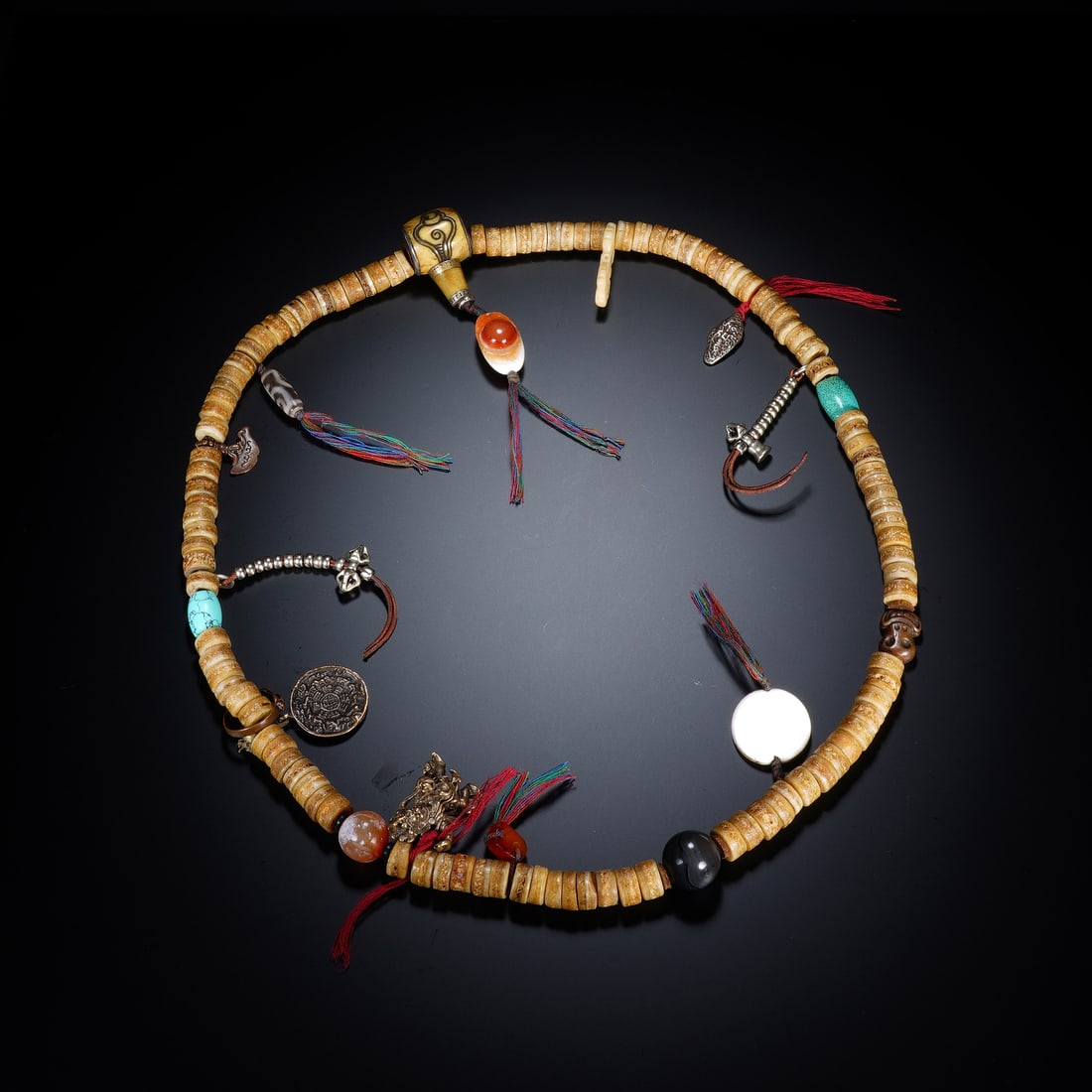 A CHINESE TIBETAN MULTI-STONE BONE MALA: A CHINESE TIBETAN MULTI-STONE BONE MALA This traditional Tibetan devotional mala is constructed from flat disc-shaped carved bone beads measuring 1.2 cm each, softened to a warm creamy aged patina fro