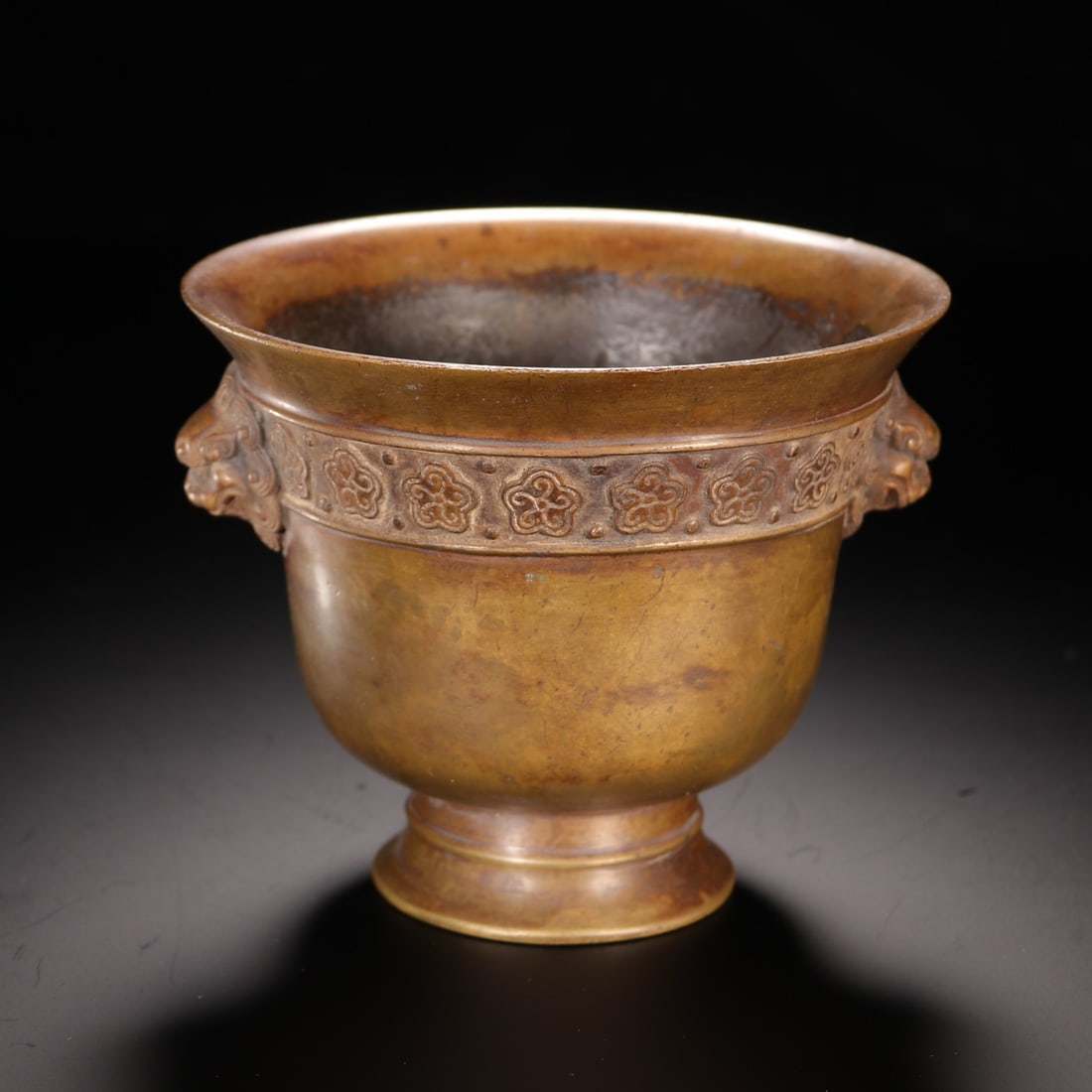A CHINESE BRONZE CENSER WITH MYTHICAL BEAST HANDLES: A CHINESE BRONZE CENSER WITH MYTHICAL BEAST HANDLES This bronze incense vessel stands 9.1cm tall, 11cm wide and weighs 774.5 grams, finished with a warm mottled golden-brown patina. It features a flar