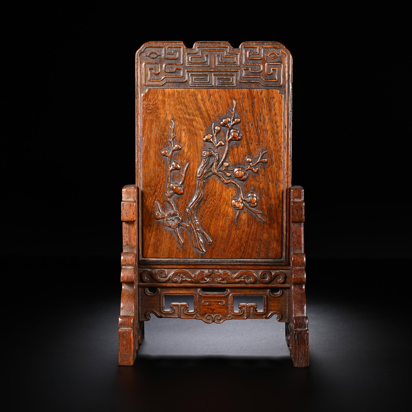 A CHINESE HUANGHUALI WOOD PLUM BLOSSOM TABLE SCREEN: A CHINESE HUANGHUALI WOOD PLUM BLOSSOM TABLE SCREEN This miniature desk screen is entirely crafted from natural Huanghuali wood showcasing distinct swirling grain and a warm aged amber patina. The cen