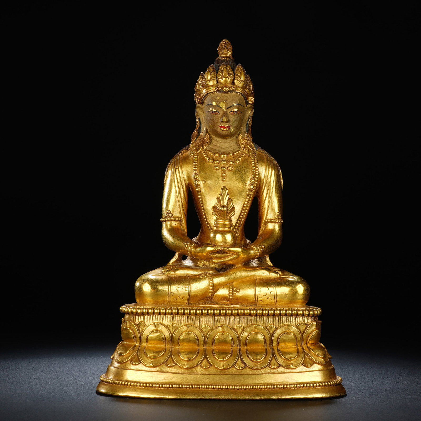 A CHINESE GILT BRONZE AMITAYUS BUDDHA STATUE: A CHINESE GILT BRONZE AMITAYUS BUDDHA STATUE This entirely gilt bronze seated Amitayus figure measures 14 cm wide, 10 cm deep and 21 cm tall, weighing 1947 grams. Adorned with an ornate floral crown a