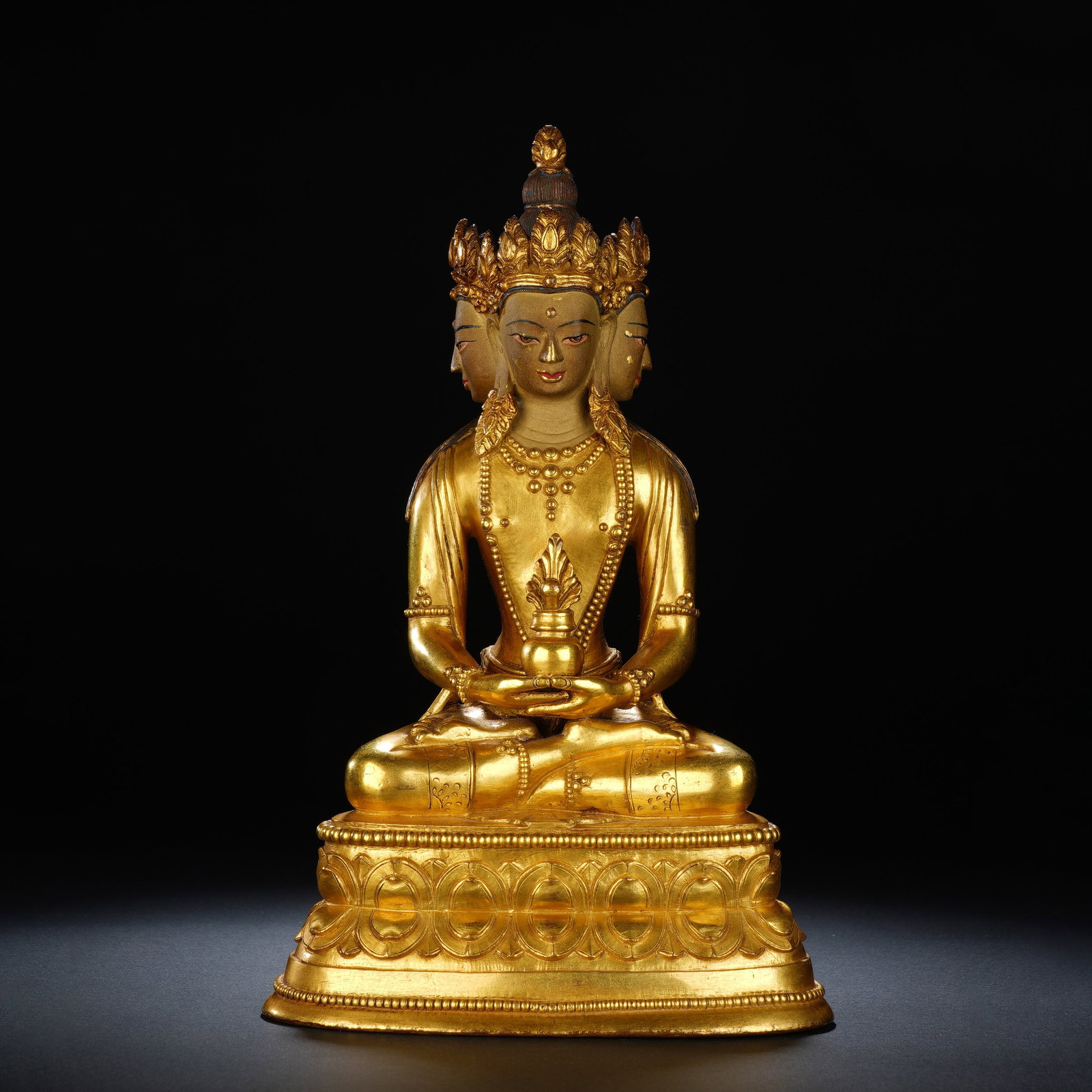 A CHINESE GILT BRONZE AMITAYUS BUDDHA FIGURE: A CHINESE GILT BRONZE AMITAYUS BUDDHA FIGURE This fully gilt bronze seated Amitayus statue measures 13.5 cm wide, 10 cm deep and 22 cm in height, weighing 1978 grams. The Buddha bears three serene fac