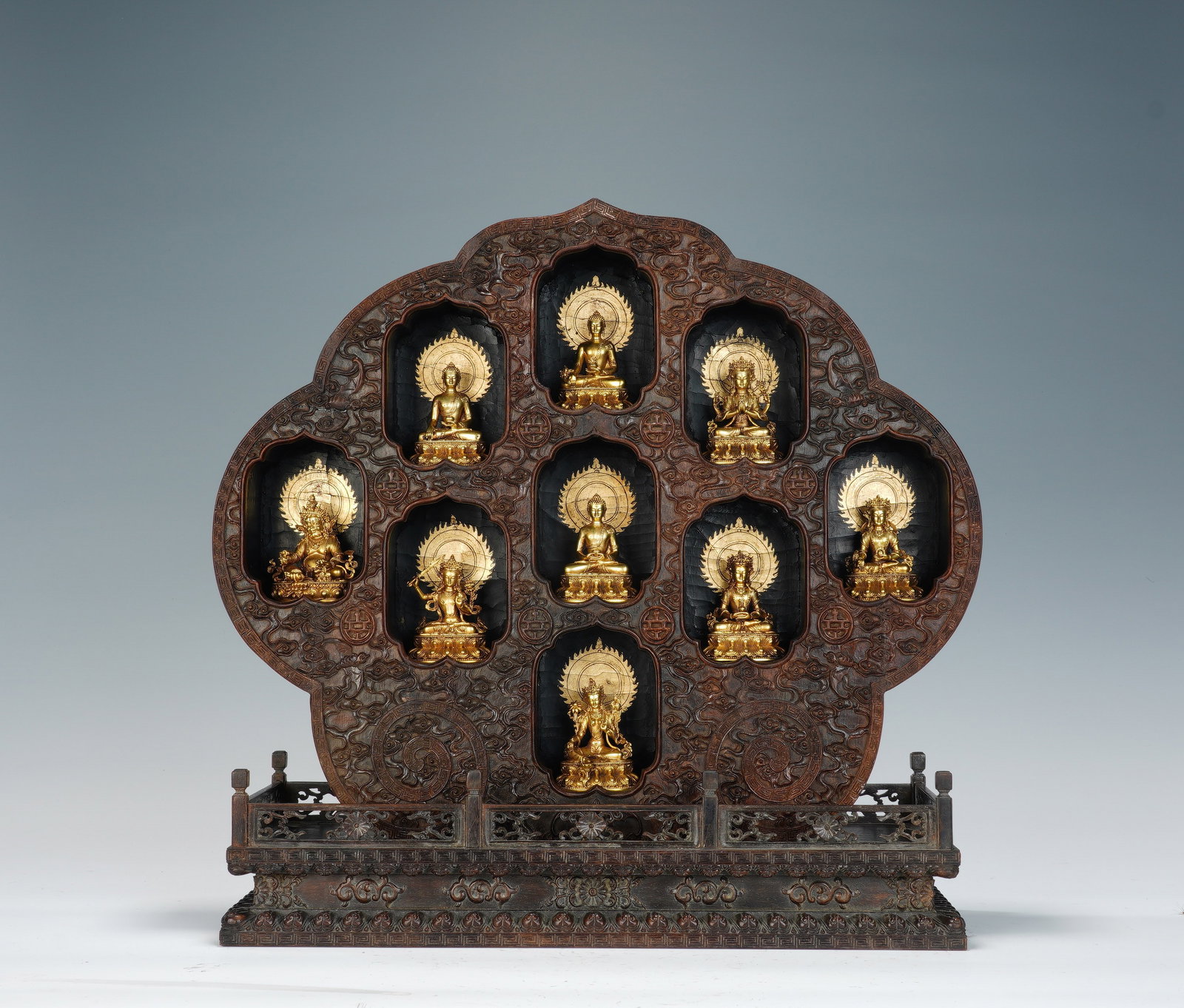 A CHINESE ZITAN NINE-NICHE GILT BUDDHA ENSEMBLE: A CHINESE ZITAN NINE-NICHE GILT BUDDHA ENSEMBLE This complete Buddhist shrine set has overall dimensions of 38cm ? 13.5cm ? 39cm, with each gilt bronze Buddha measuring 5cm ? 3.5cm ? 6.3cm. The quatre