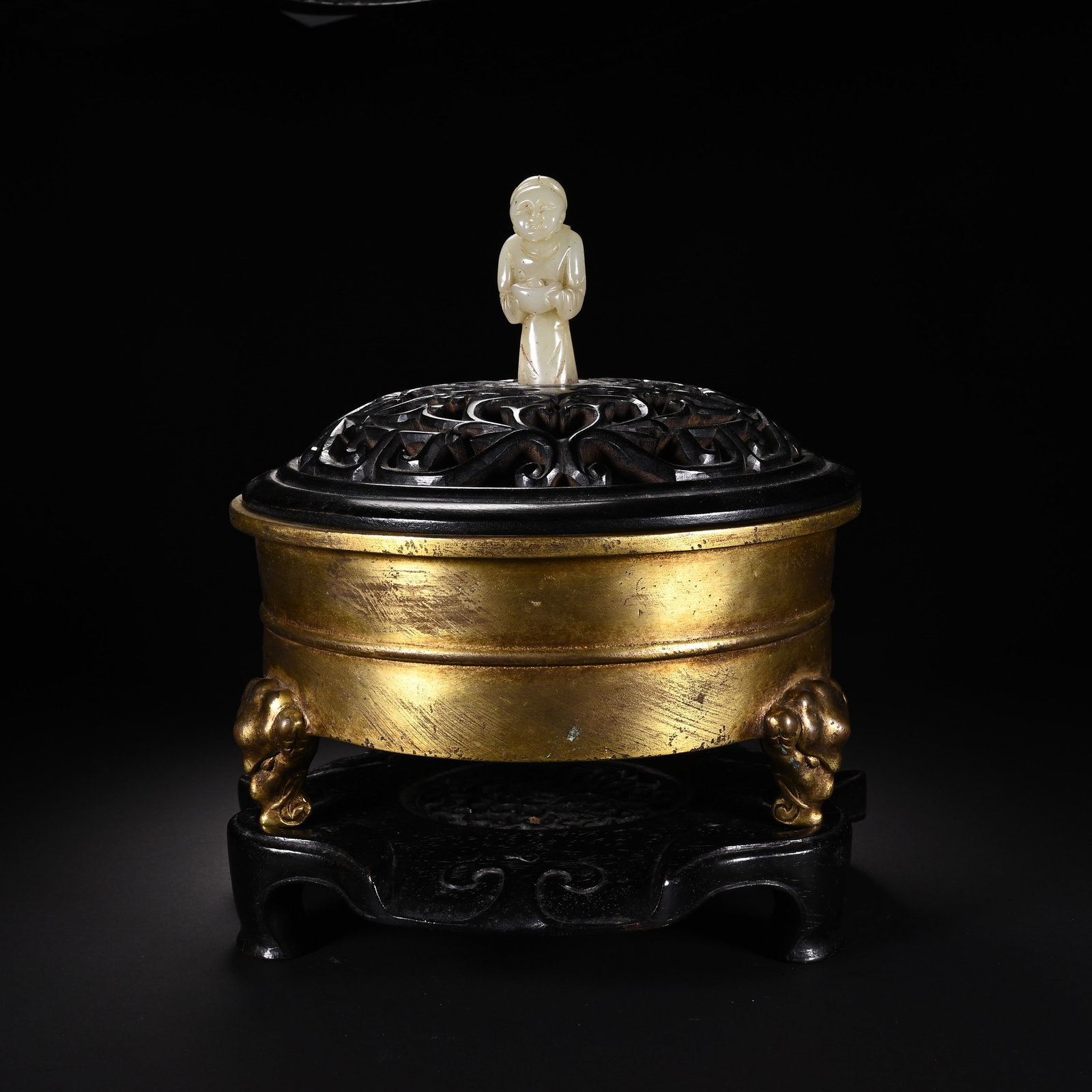 A CHINESE GILT BRONZE TRIPOD INCENSE CENSER WITH JADE FINIAL: A CHINESE GILT BRONZE TRIPOD INCENSE CENSER WITH JADE FINIAL This cylindrical gilt bronze censer stands upon three sculpted mythical beast mask feet, its smooth gilded body marked by subtle vintage we