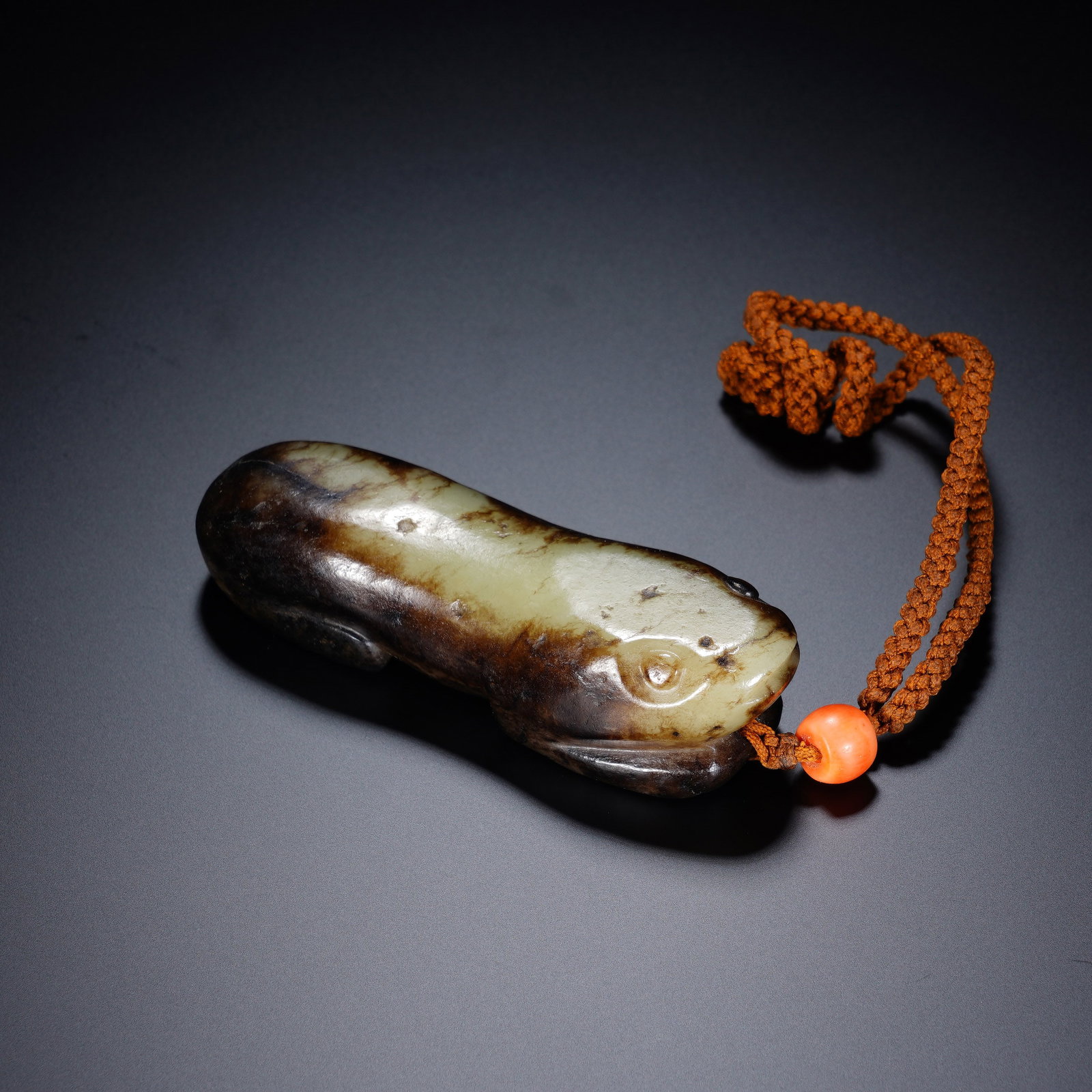 A CHINESE ARCHAIC RECUMBENT JADE MYTHICAL BEAST PENDANT: A CHINESE ARCHAIC RECUMBENT JADE MYTHICAL BEAST PENDANT This smooth jade beast carving measures 3cm ? 9cm ? 2.5cm and weighs 120 grams, rendered in a compact prone form with simplified rounded facial 