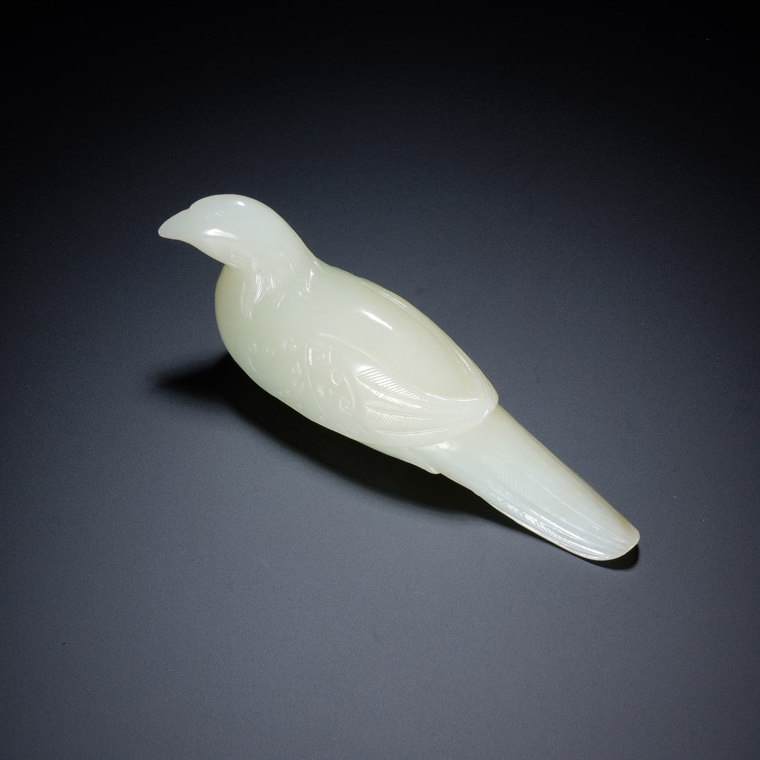 A CHINESE WHITE JADE MAGPIE HAND PENDANT: A CHINESE WHITE JADE MAGPIE HAND PENDANT Skillfully carved from fine creamy white nephrite jade, this hand-held magpie ornament features a smooth polished surface with delicate incised lines defining 