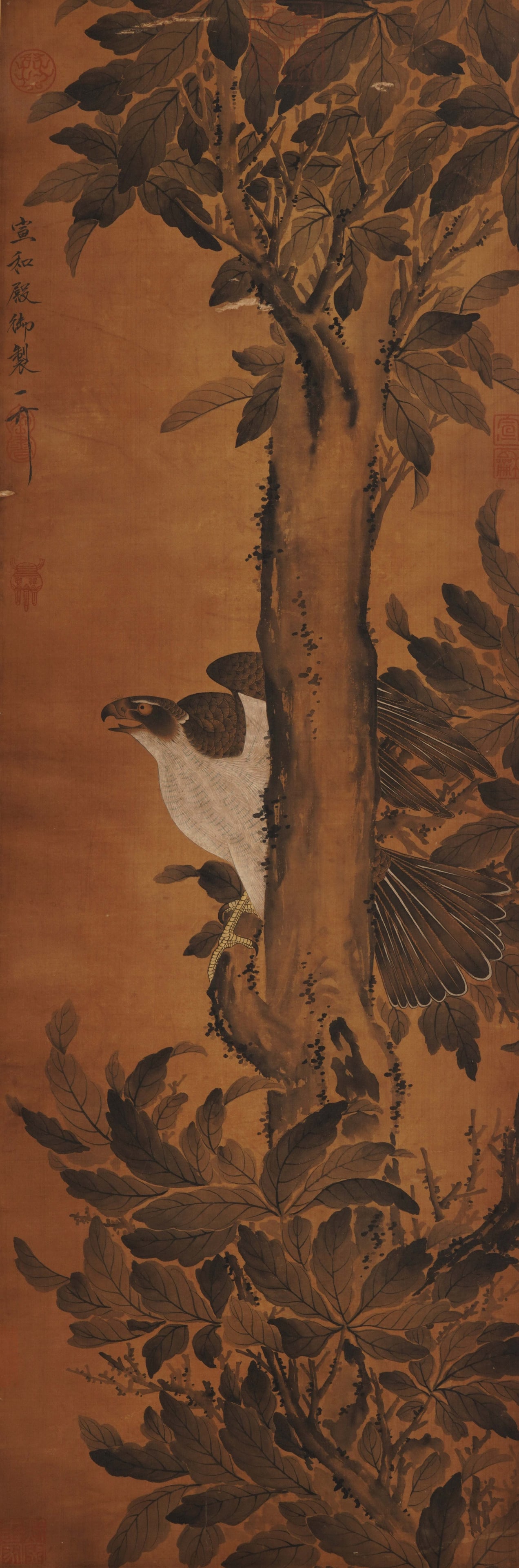 A CHINESE PAINTING OF HAWK AND TREE, SIGNED EMPEROR HUIZONG: A CHINESE PAINTING OF HAWK AND TREE, SIGNED EMPEROR HUIZONG Vertical ink painting on aged amber silk, inscribed and sealed by Emperor Huizong of Song on the left margin. A fierce hawk perches halfway 