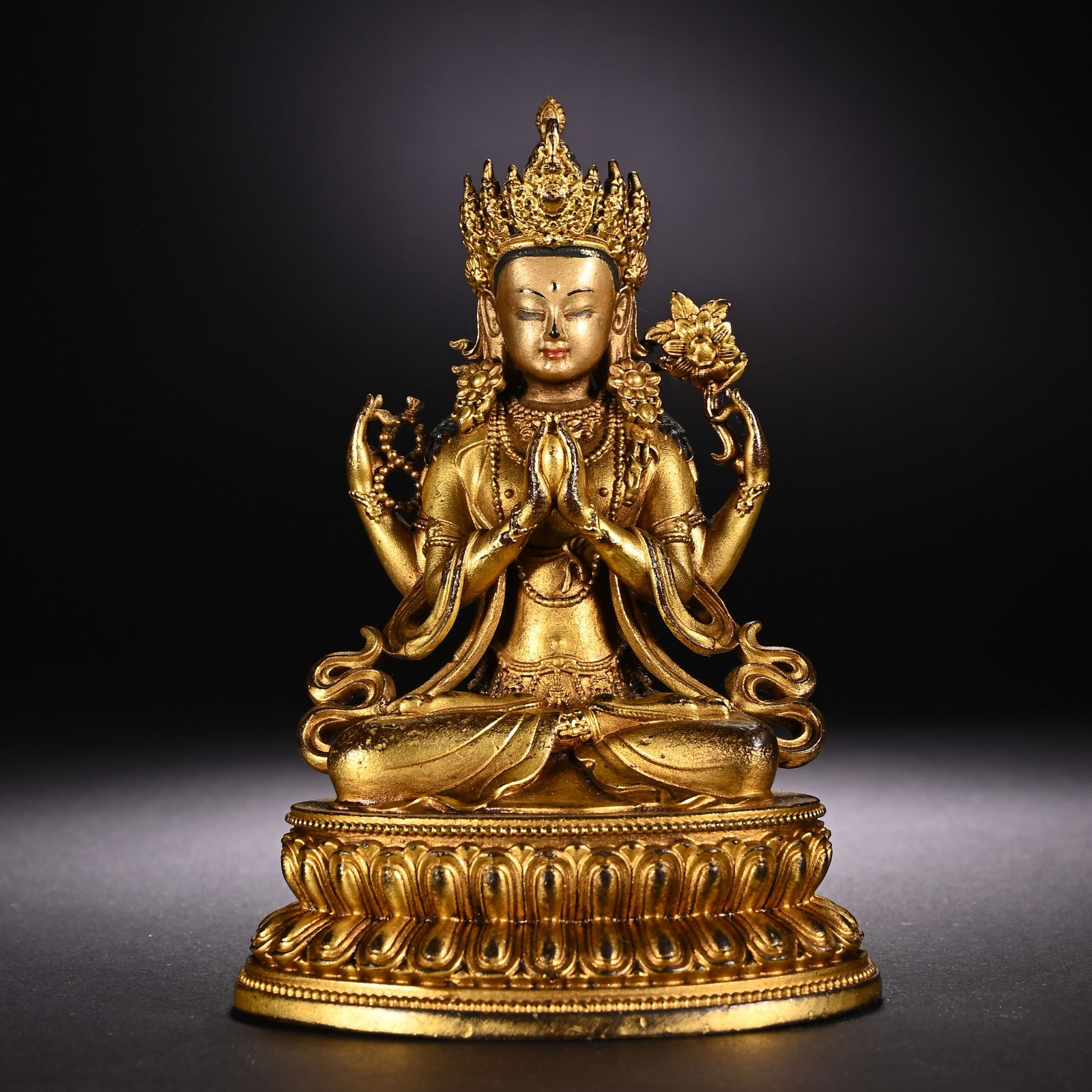 A CHINESE GILT BRONZE FOUR-ARM GUANYIN STATUE: A CHINESE GILT BRONZE FOUR-ARM GUANYIN STATUE This finely cast gilt bronze figure depicts Four-Arm Avalokiteshvara seated in full lotus posture atop a double-layered lotus pedestal edged with fine bea