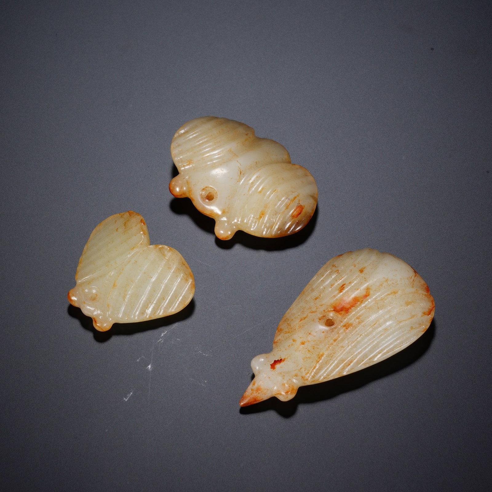 A GROUP OF THREE CHINESE ARCHAIC JADE CICADAS: A GROUP OF THREE CHINESE ARCHAIC JADE CICADAS This set comprises three carved nephrite cicada pendants with varying dimensions: 3.5 x 3 x 1 cm, 4.7 x 3.5 x 1.1 cm and 3.5 x 6 x 1.2 cm, with a combined