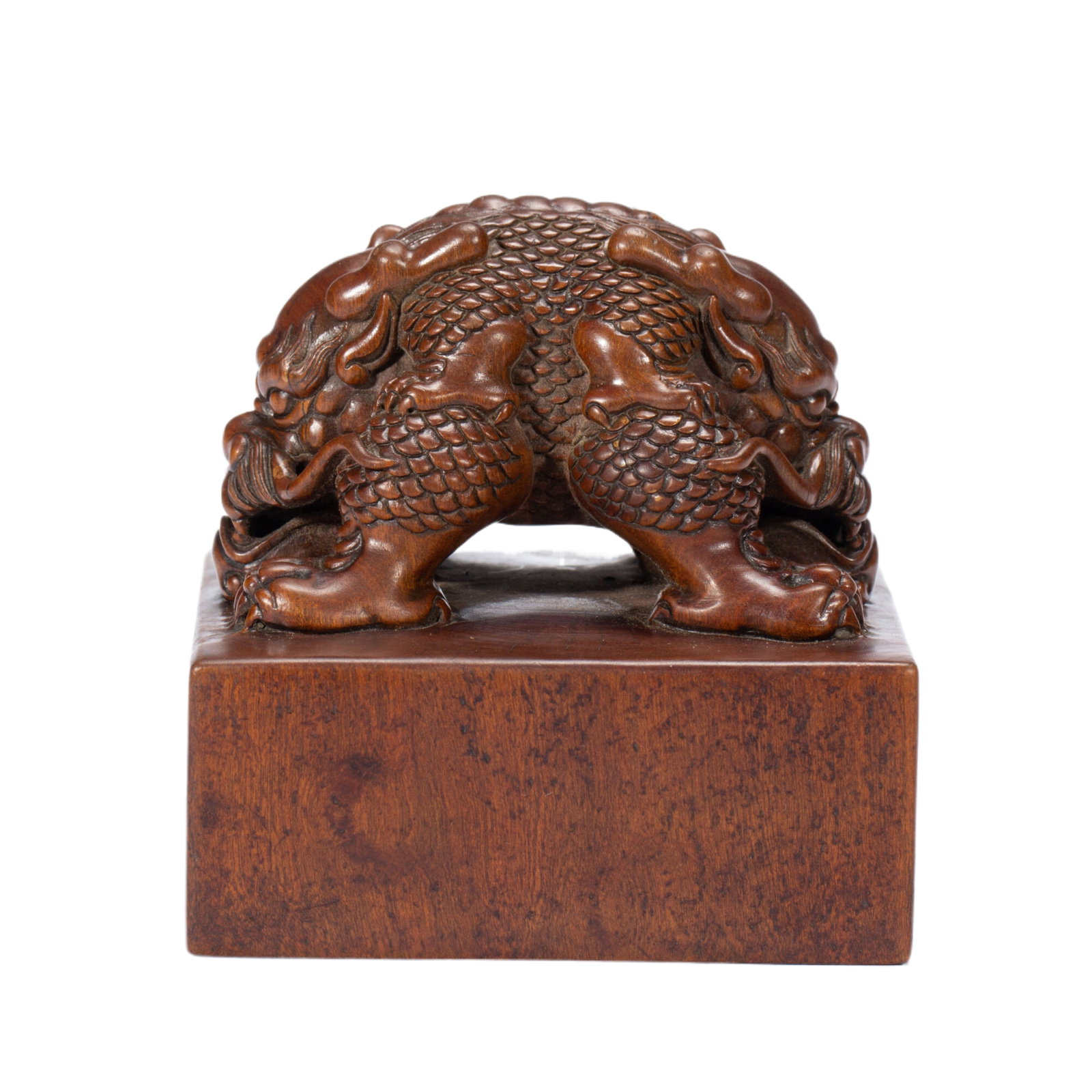 A CHINESE SANDALWOOD TWIN-DRAGON SEAL: A CHINESE SANDALWOOD TWIN-DRAGON SEAL A solid square seal meticulously carved from natural sandalwood with warm rich brown patina. The cube matrix supports an elaborate double dragon finial with finel