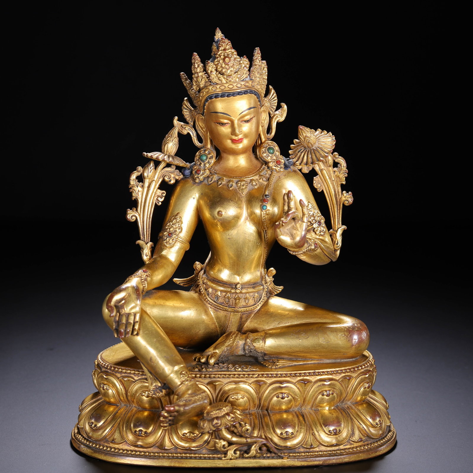 A CHINESE GILT BRONZE TARA STATUE: A CHINESE GILT BRONZE TARA STATUE This fully gilded copper alloy figure depicts Green Tara seated in the relaxed lalitasana pose atop a double-tiered lotus pedestal chased with layered petal relief. T