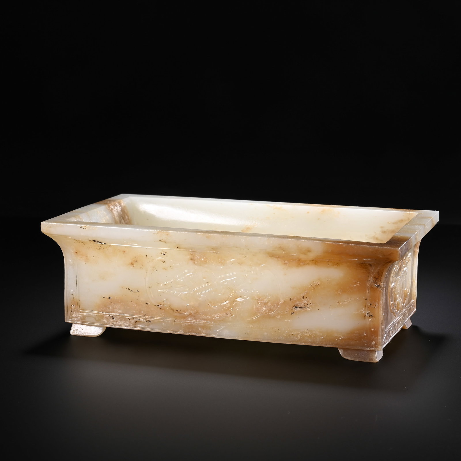 A CHINESE WHITE JADE RECTANGULAR FLOWER BASIN: A CHINESE WHITE JADE RECTANGULAR FLOWER BASIN Crafted from creamy white nephrite naturally streaked with warm amber russet inclusions and minor dark mineral flecks, this rectangular flower basin featu