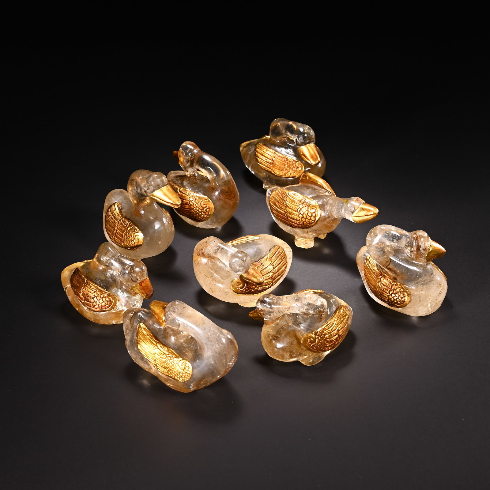 A SET OF CHINESE GILDED ROCK CRYSTAL GOOSE ORNAMENTS: A SET OF CHINESE GILDED ROCK CRYSTAL GOOSE ORNAMENTS This charming ensemble includes nine identical goose figurines carved from translucent natural rock crystal, each detailed with polished gilded bea