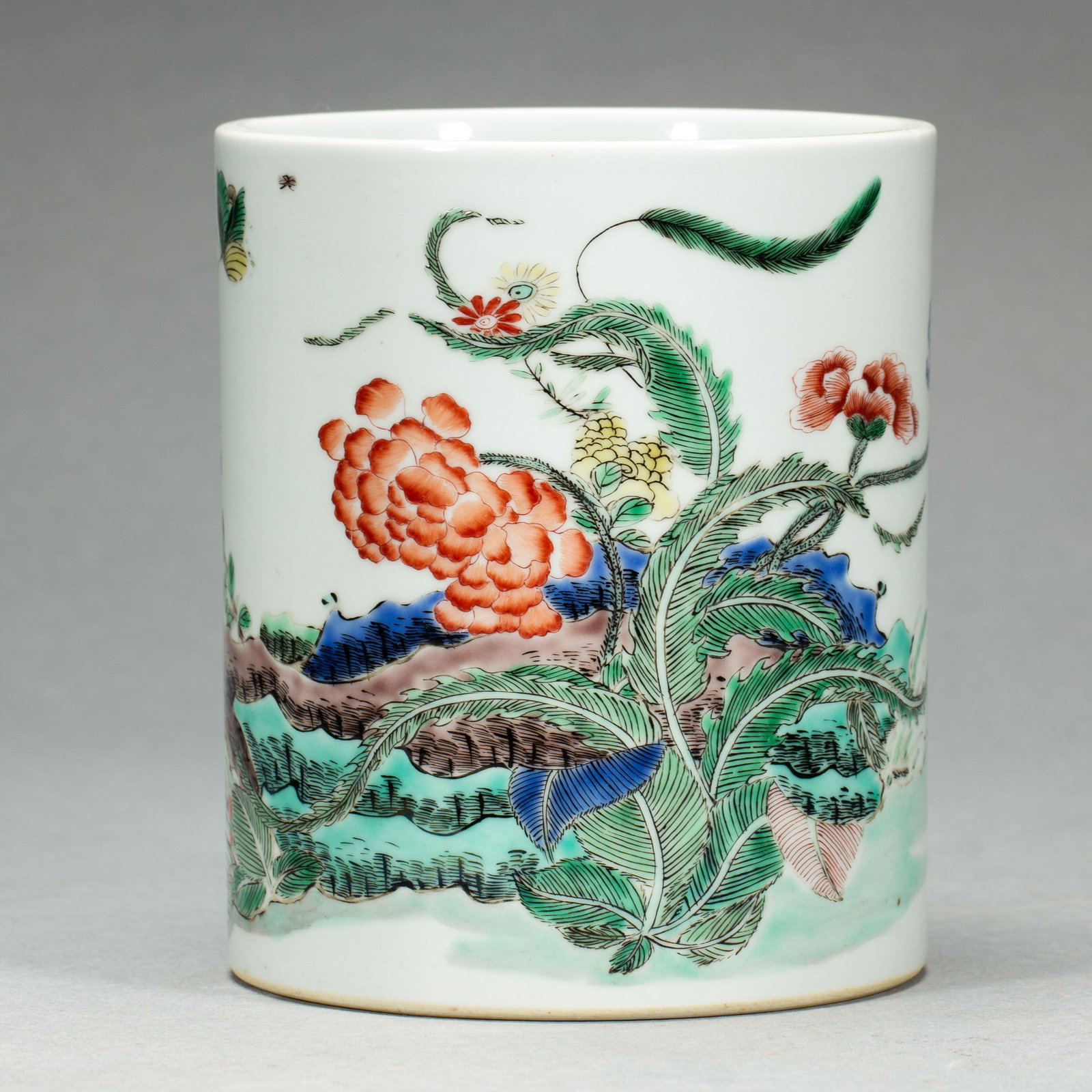 A CHINESE WUCAI PORCELAIN BRUSH POT: A CHINESE WUCAI PORCELAIN BRUSH POT A cylindrical scholar's brush pot crafted from fine white porcelain, vividly decorated in classic Wucai enamel palette. The exterior features an elaborate natural s